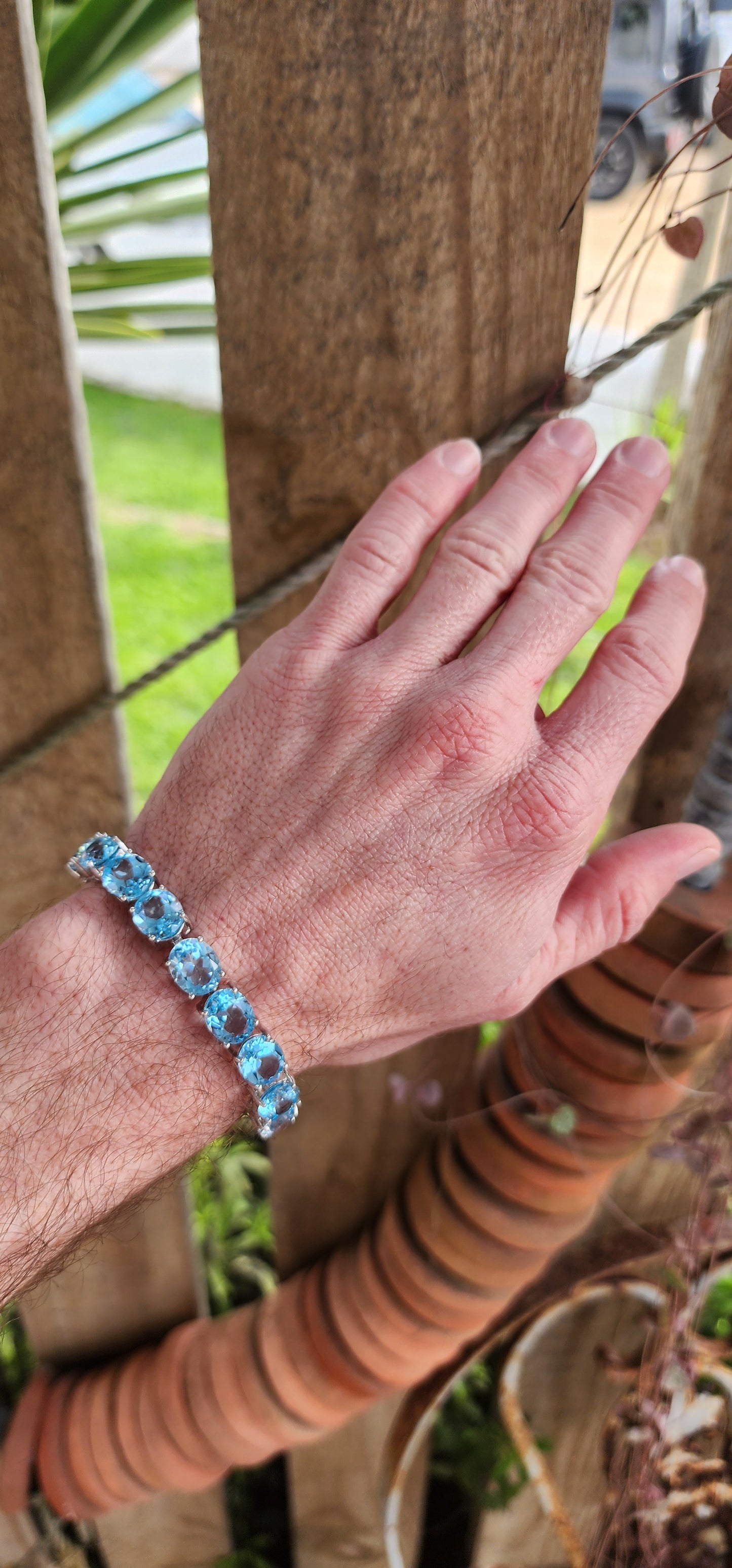 This gorgeous and STATEMENT Tennis style bracelet is crafted in Sterling Silver and features 9x large sized Oval Faceted Cut Blue Topaz Gemstones, claw set and studded together in an Tennis style, to give it a bold and stylish look.