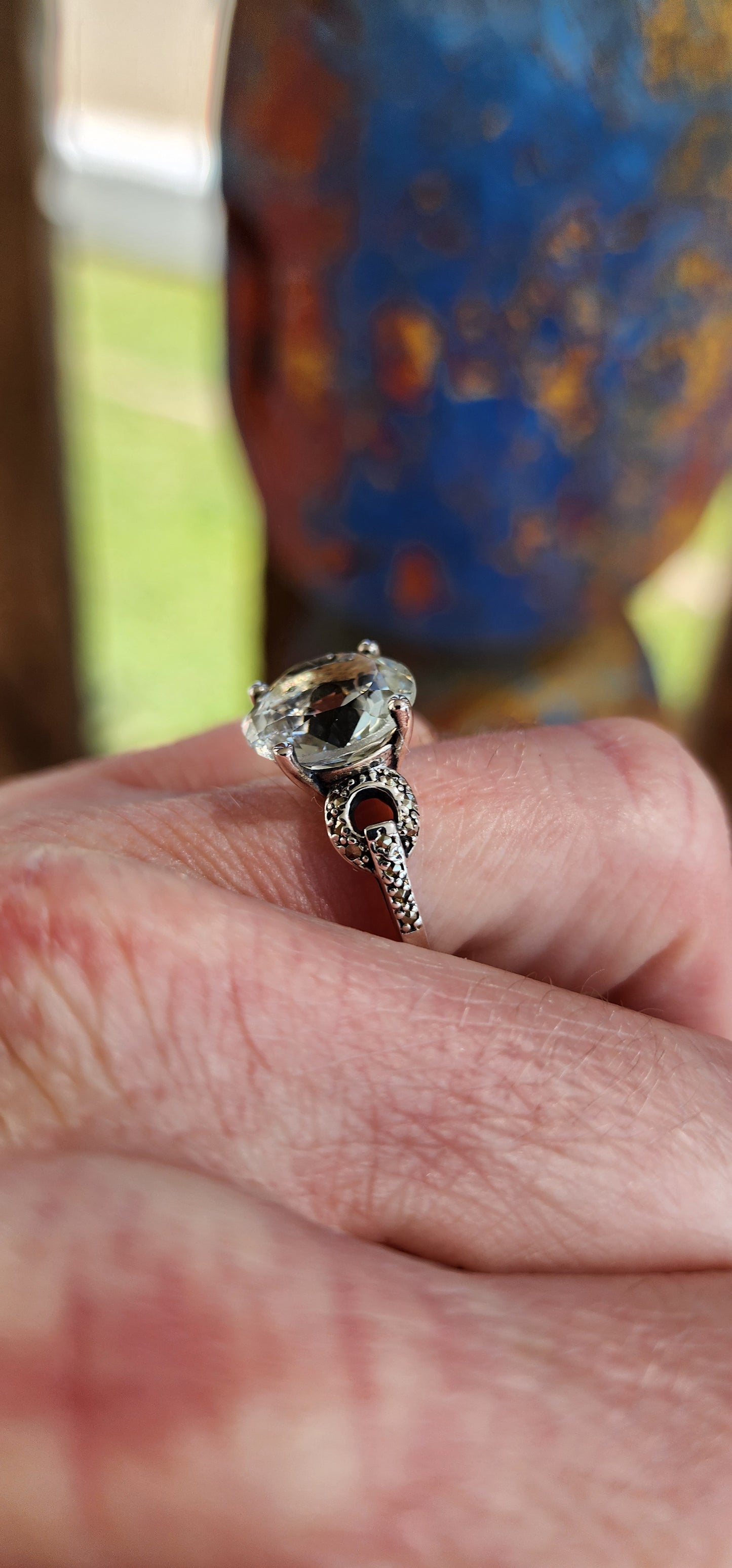 This alluring Sterling Silver cocktail/dress ring features a generous in size Round cut Prasiolite "Green Amethyst"Gemstone in the centre, prong set in a ornate pierced Gallery basket .Marcasite studded Circles adorn the shoulders/sides of the ring.