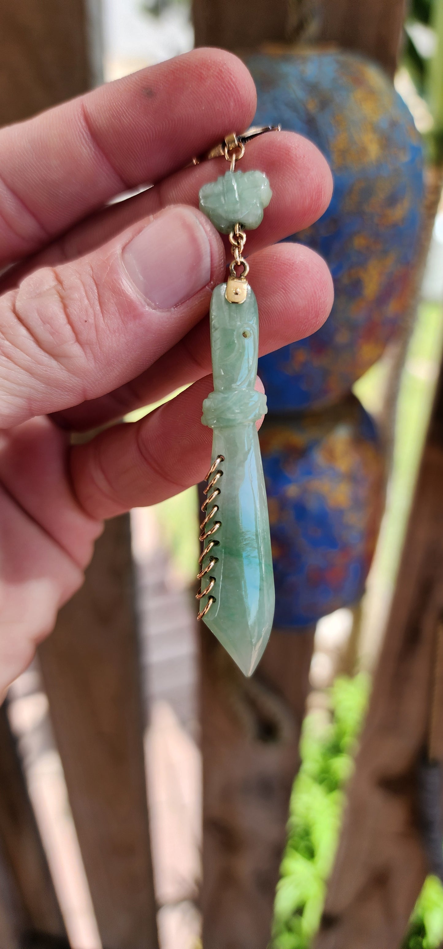 This pendant is a late Victorian-era piece featuring hand-carved jade and 9ct yellow gold. It’s crafted in the shape of a traditional Chinese nine-ring broadsword, with an apple-green jade blade.