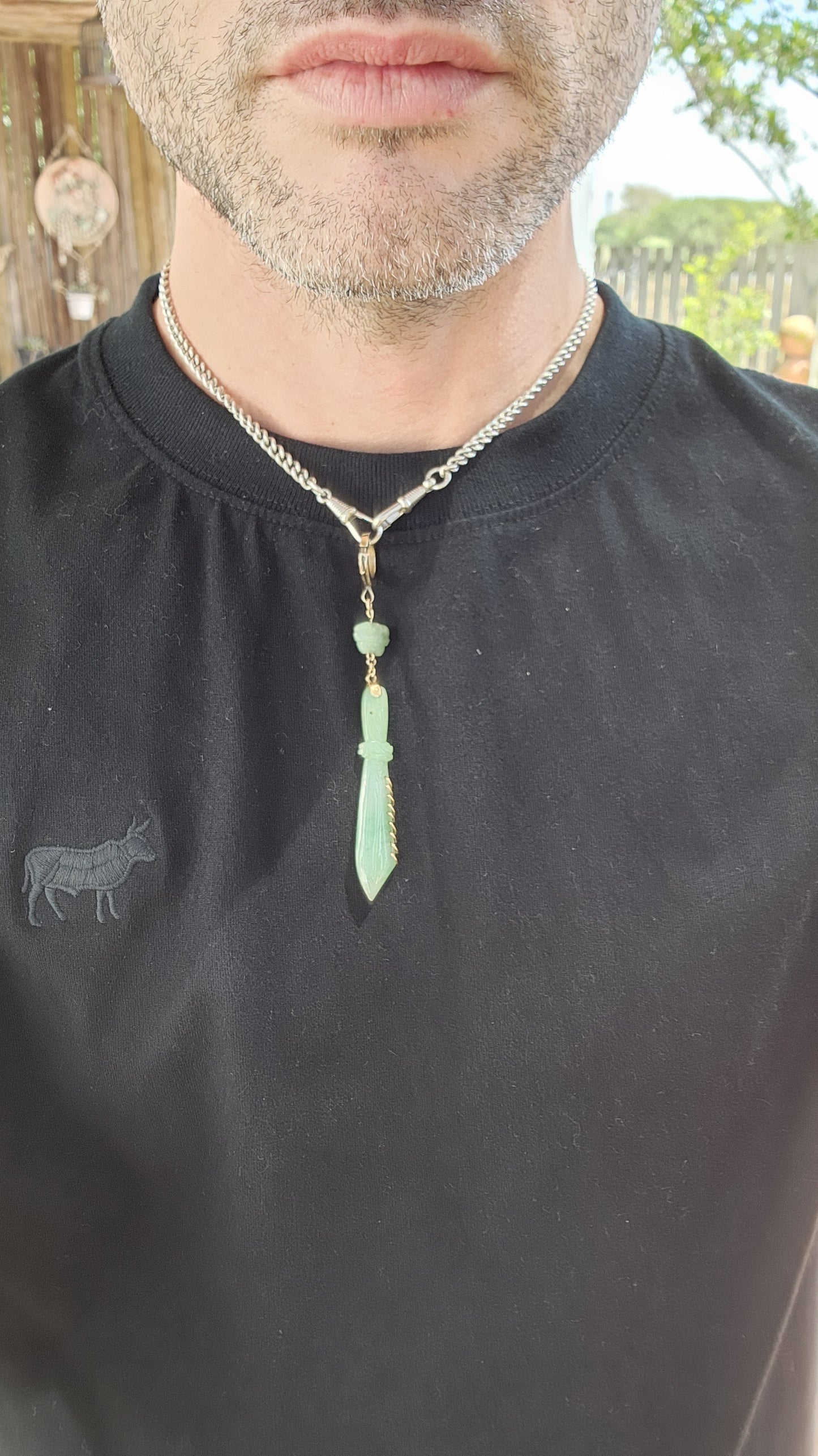 This pendant is a late Victorian-era piece featuring hand-carved jade and 9ct yellow gold. It’s crafted in the shape of a traditional Chinese nine-ring broadsword, with an apple-green jade blade.