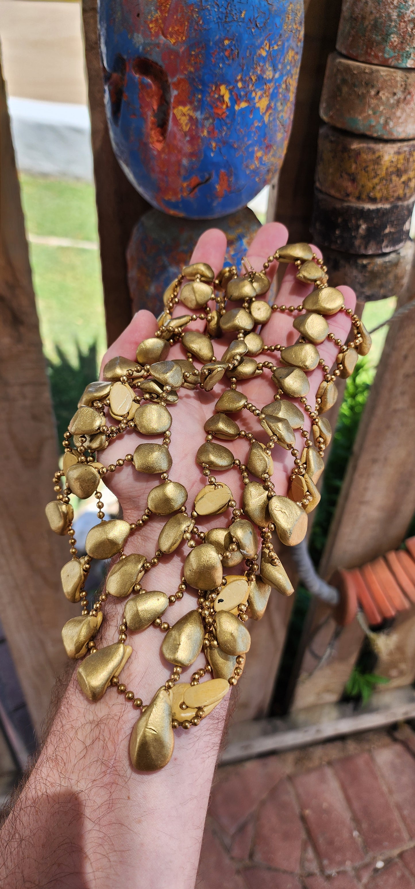 Get ready to channel your inner queen with this jaw-dropping artisan made statement necklace!Crafted from goldtone clay pebbles and Brass chains.