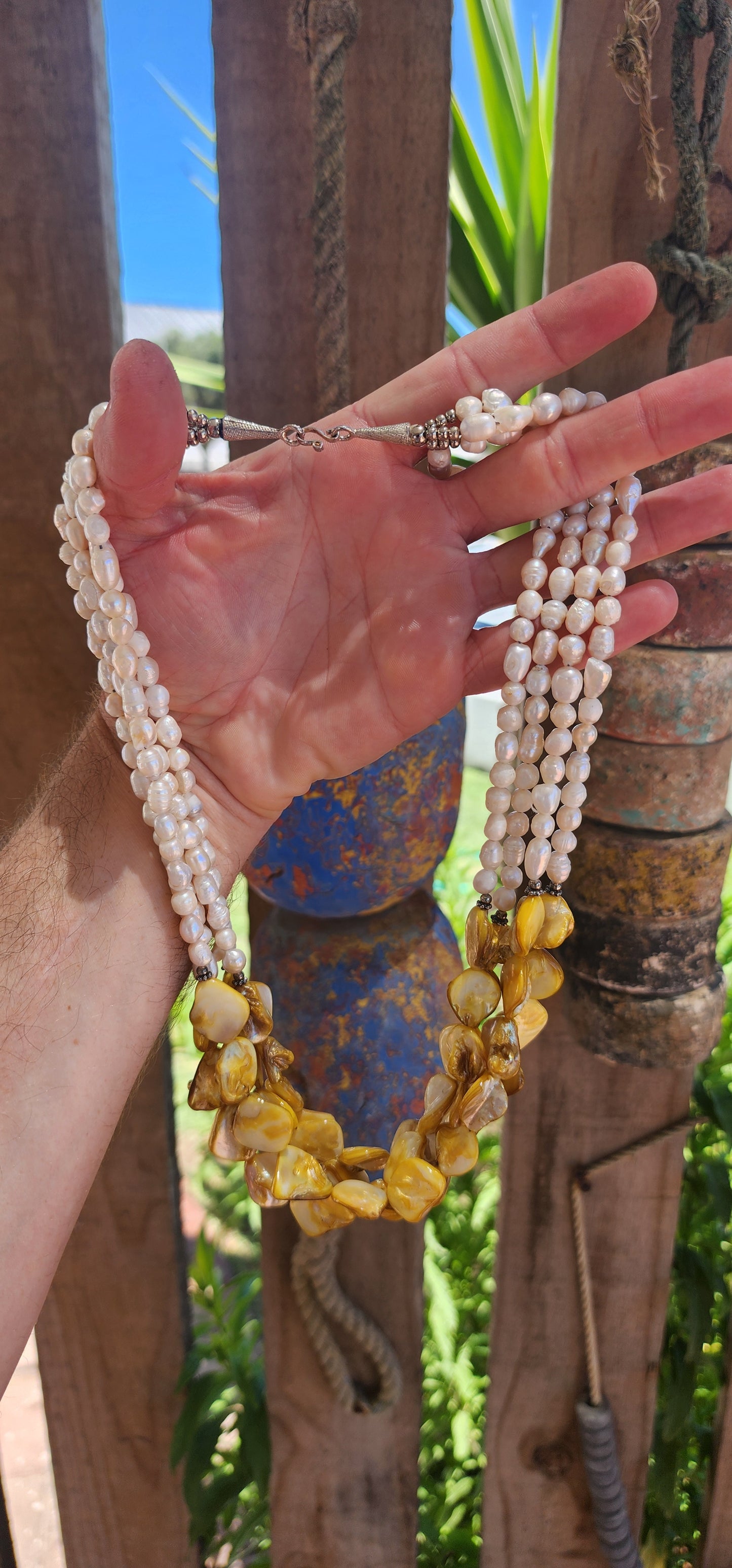 This chunky necklace is an exquisite example of bohemian-inspired elegance, radiating a natural, earthy charm. It features four lustrous strands of irregular, baroque-shaped freshwater pearls, each strand glimmering with subtle iridescence.
