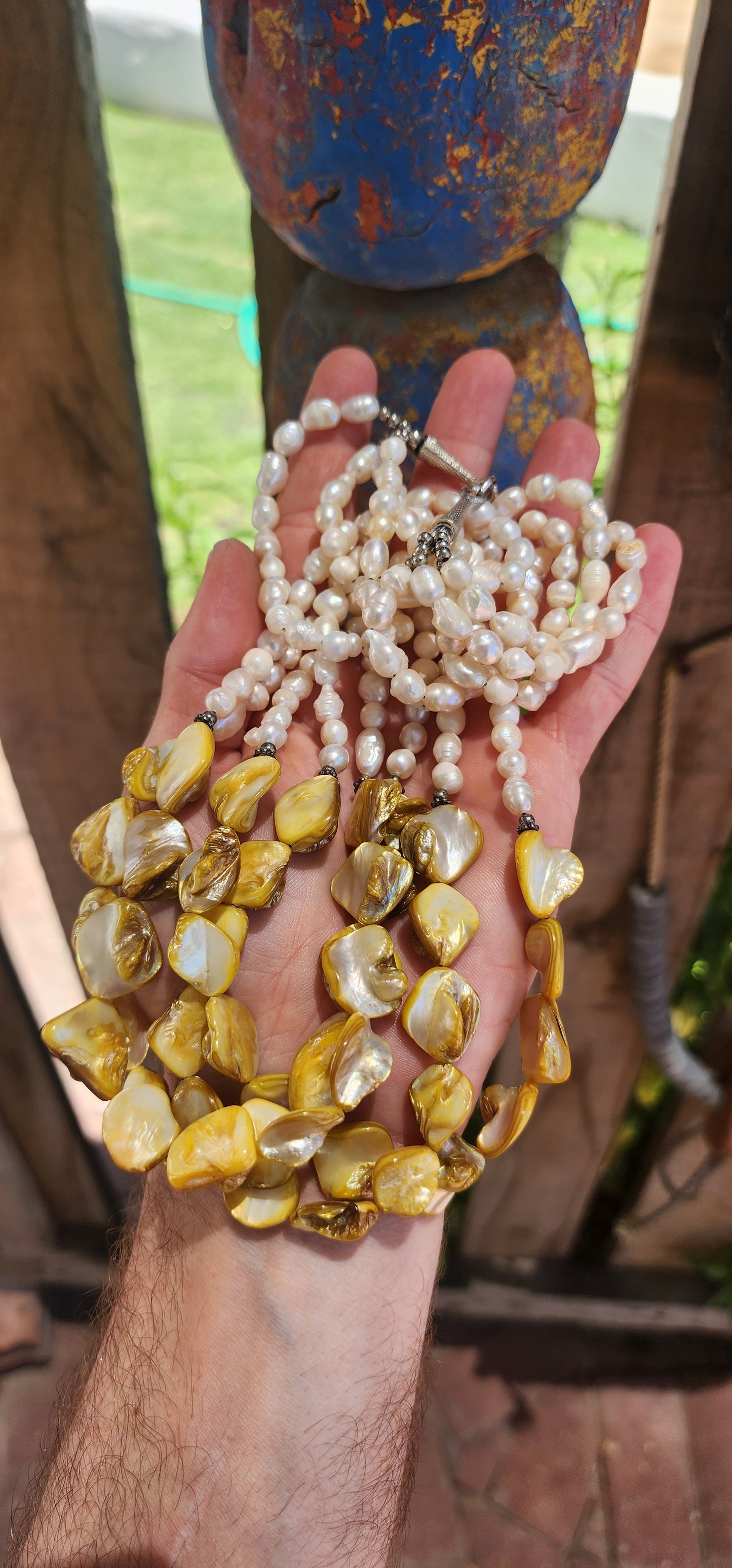 This chunky necklace is an exquisite example of bohemian-inspired elegance, radiating a natural, earthy charm. It features four lustrous strands of irregular, baroque-shaped freshwater pearls, each strand glimmering with subtle iridescence.