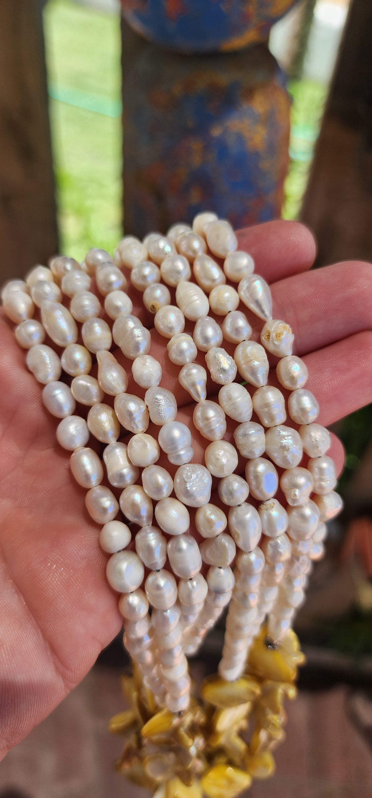 This chunky necklace is an exquisite example of bohemian-inspired elegance, radiating a natural, earthy charm. It features four lustrous strands of irregular, baroque-shaped freshwater pearls, each strand glimmering with subtle iridescence.