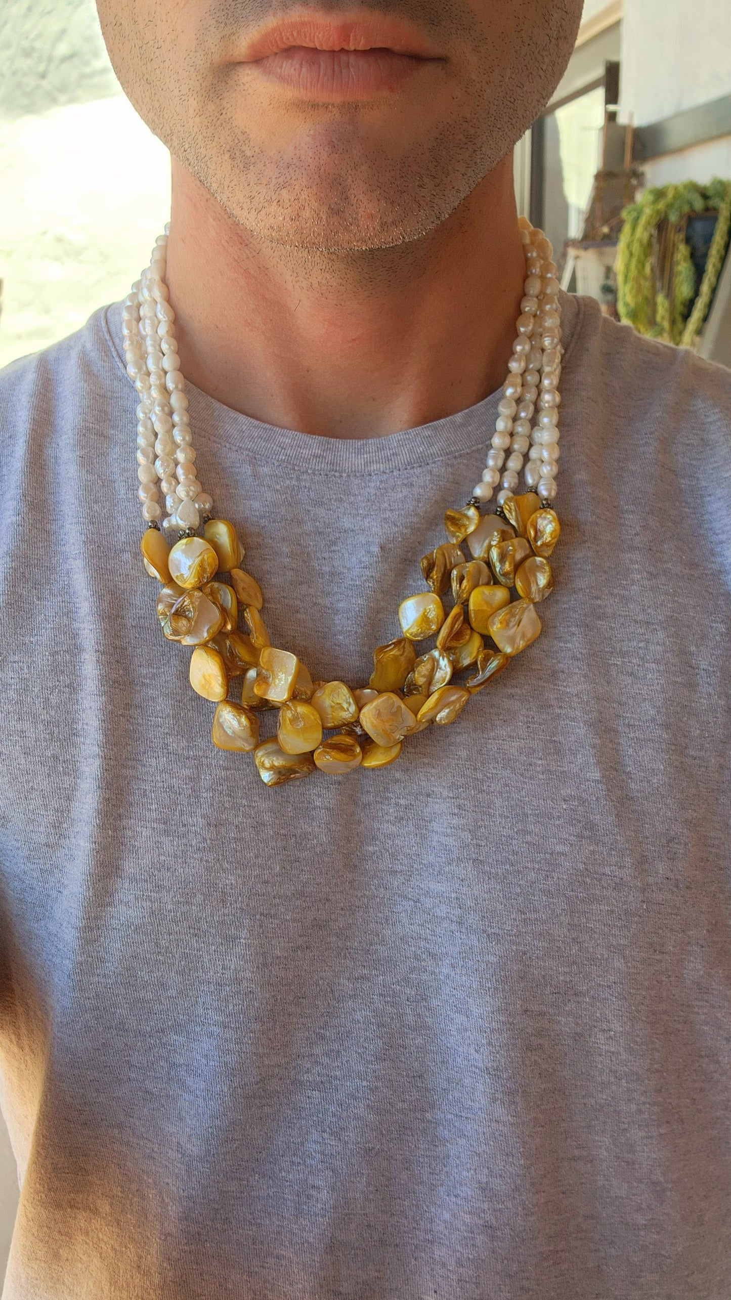 This chunky necklace is an exquisite example of bohemian-inspired elegance, radiating a natural, earthy charm. It features four lustrous strands of irregular, baroque-shaped freshwater pearls, each strand glimmering with subtle iridescence.