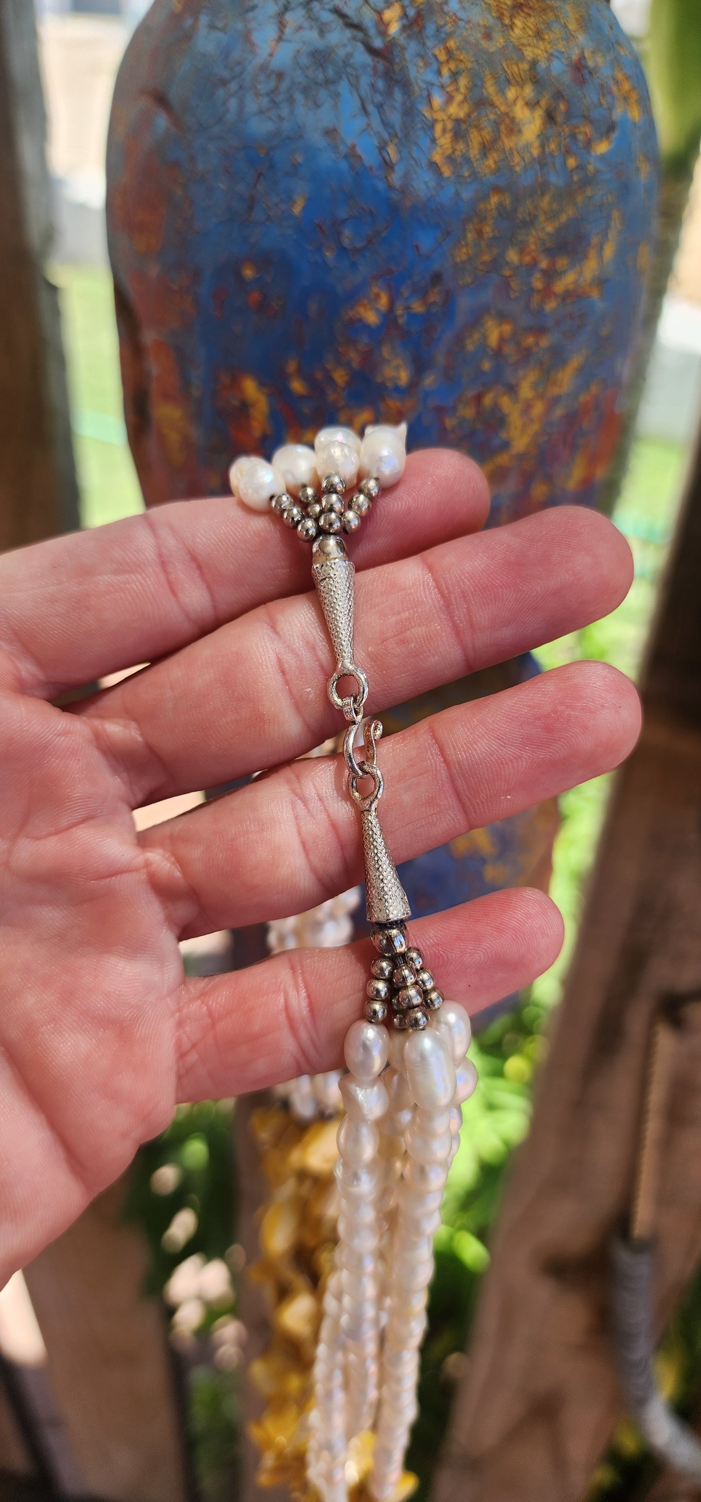 This chunky necklace is an exquisite example of bohemian-inspired elegance, radiating a natural, earthy charm. It features four lustrous strands of irregular, baroque-shaped freshwater pearls, each strand glimmering with subtle iridescence.