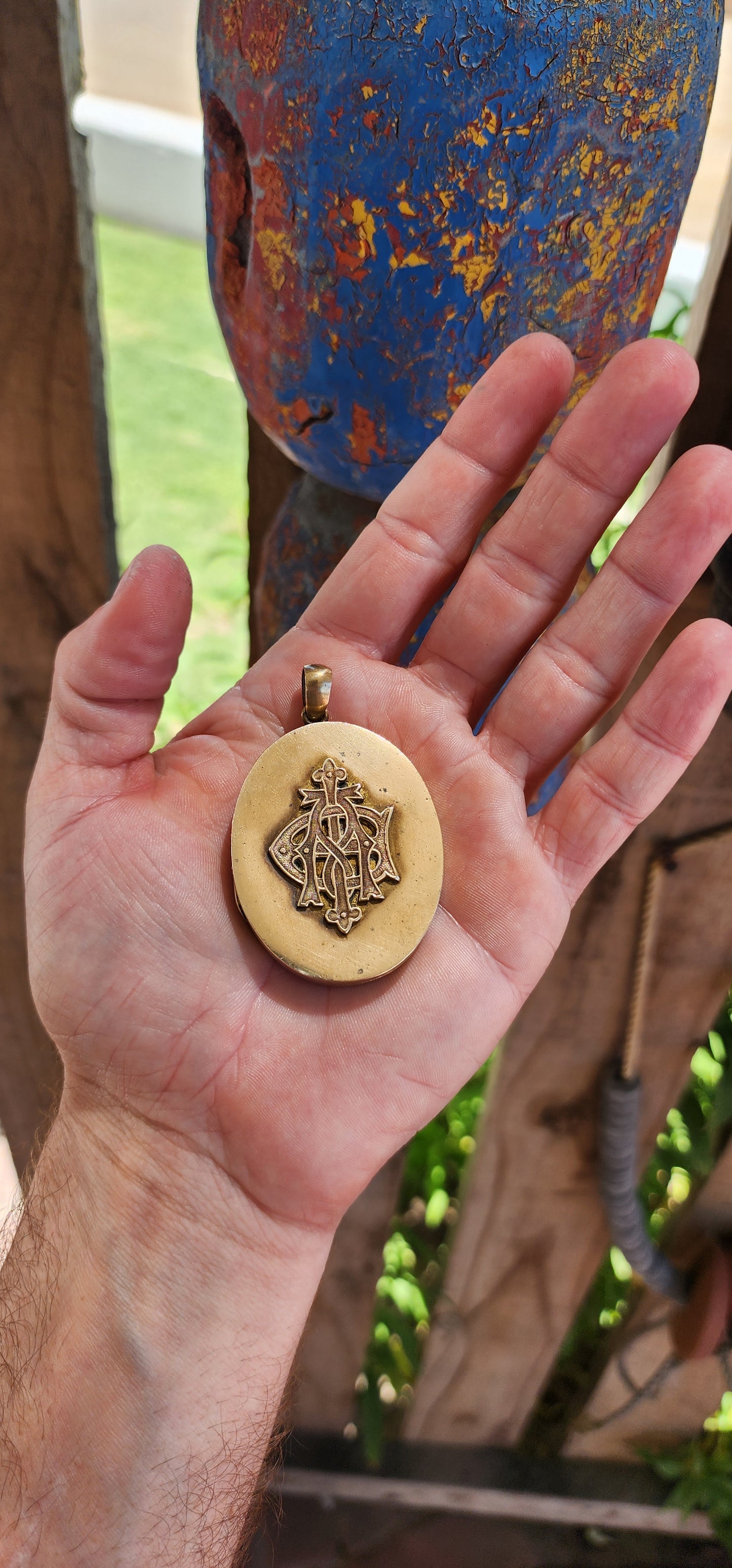 This remarkable piece is a large Victorian-era brass sweetheart locket, crafted in an elegant oval form and adorned with a striking raised monogram, "AEI." Standing for Amity (Affinity), Eternity, and Infinity.