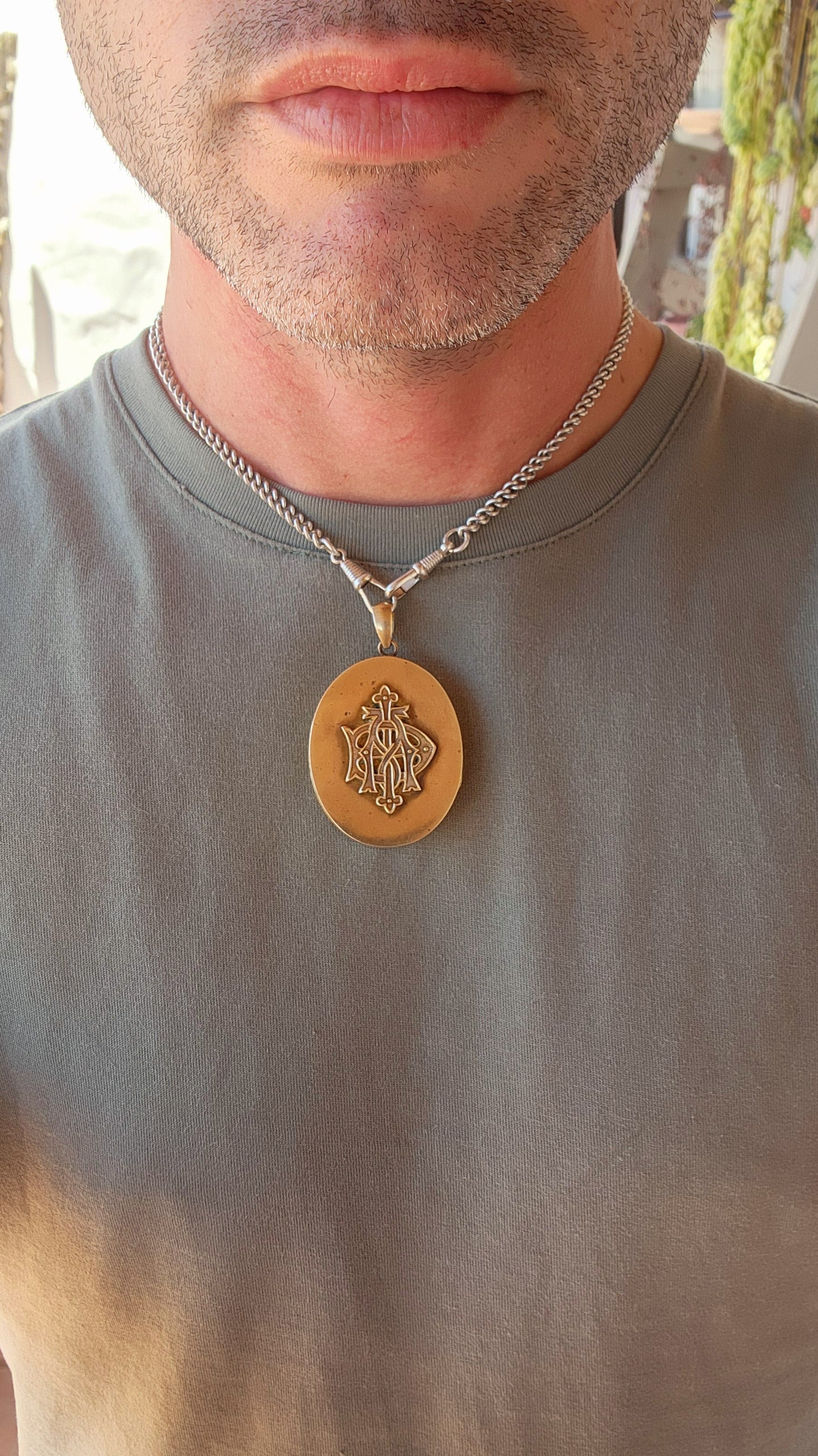 This remarkable piece is a large Victorian-era brass sweetheart locket, crafted in an elegant oval form and adorned with a striking raised monogram, "AEI." Standing for Amity (Affinity), Eternity, and Infinity.