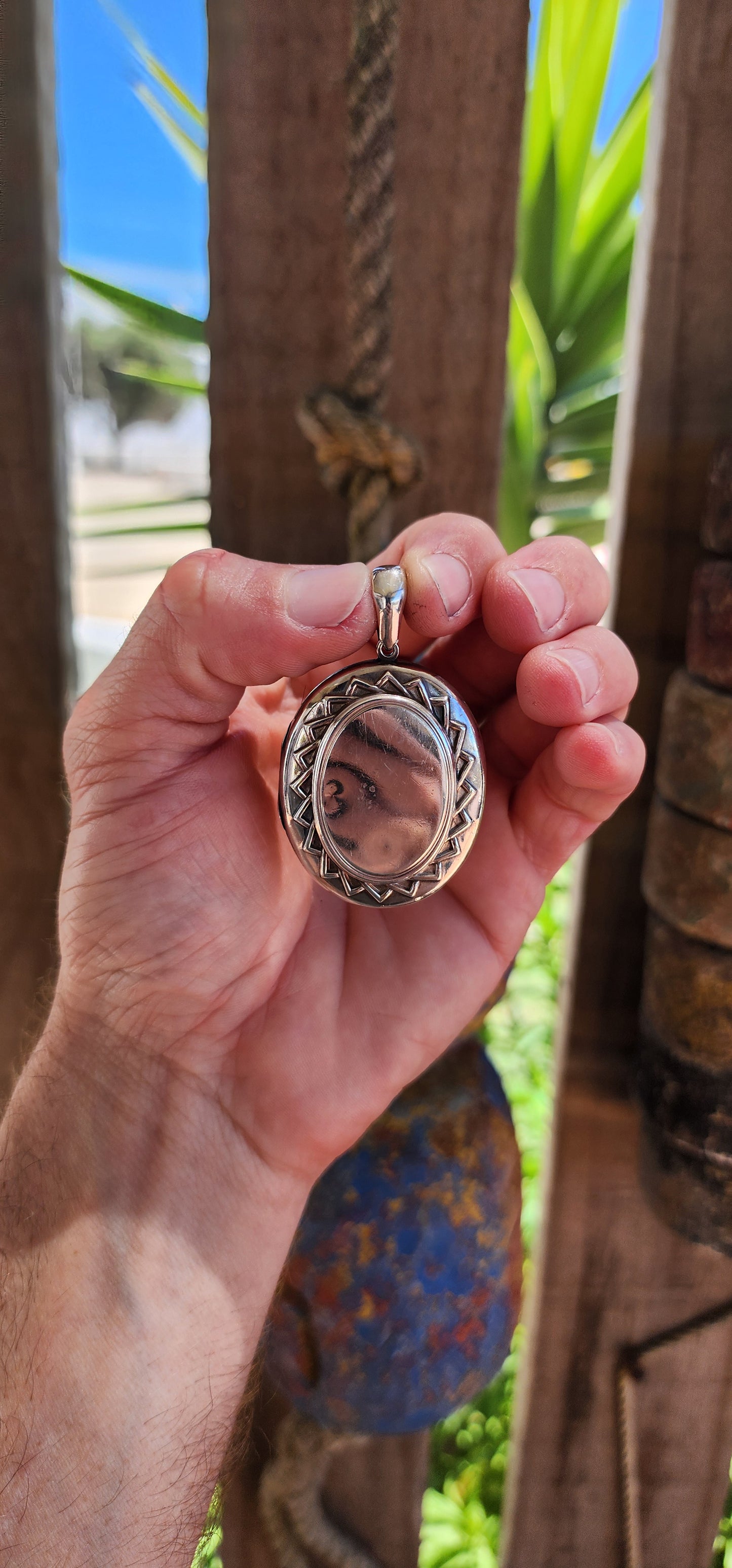 This large sized locket is a beautiful example of Victorian-era craftsmanship, designed in a sterling silver oval shape with a striking sunburst pattern encircling the center on both sides.