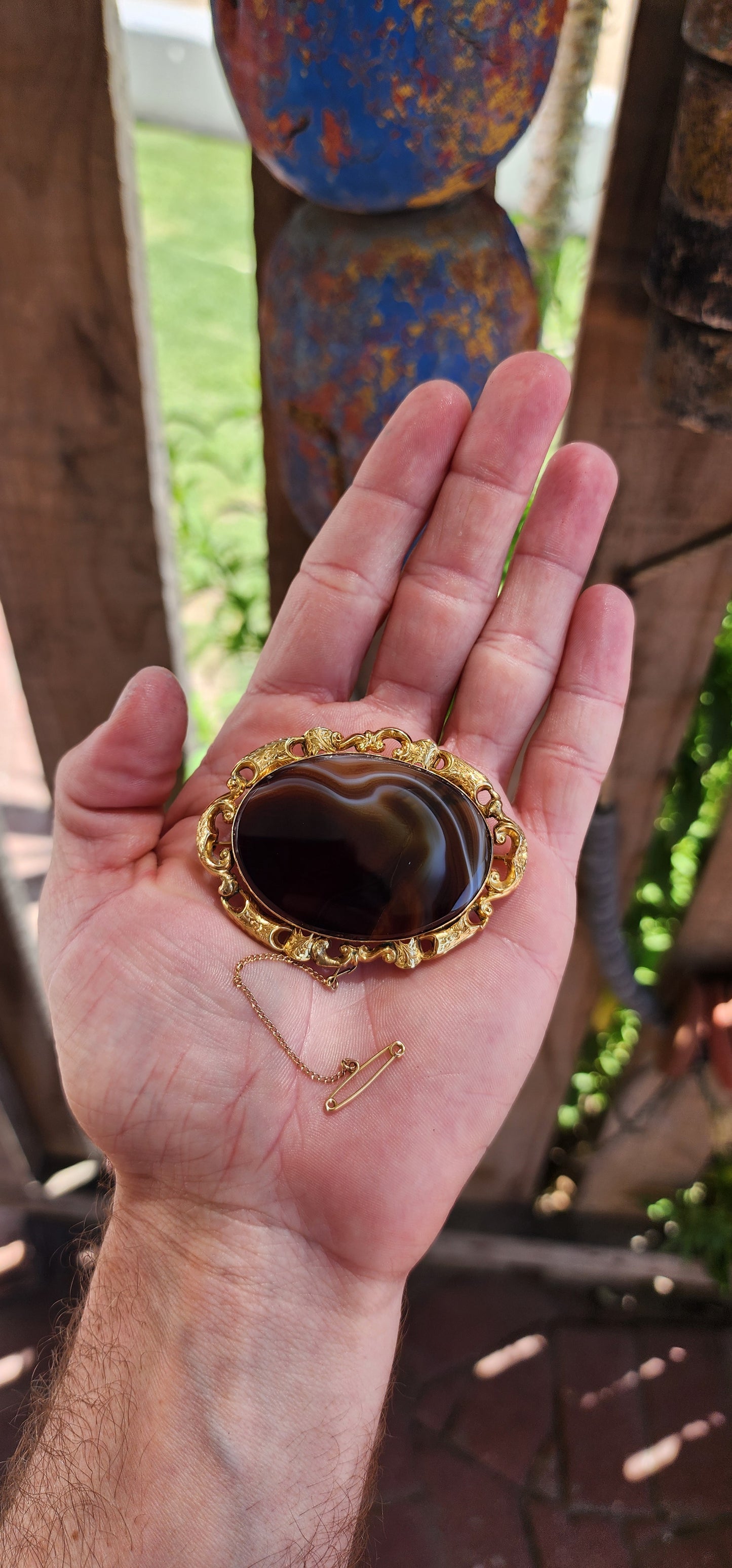 This oversized brooch is a fine example of an Antique Victorian-era Scottish banded agate brooch, crafted in 10ct yellow gold and featuring a large, polished oval banded agate at its center.