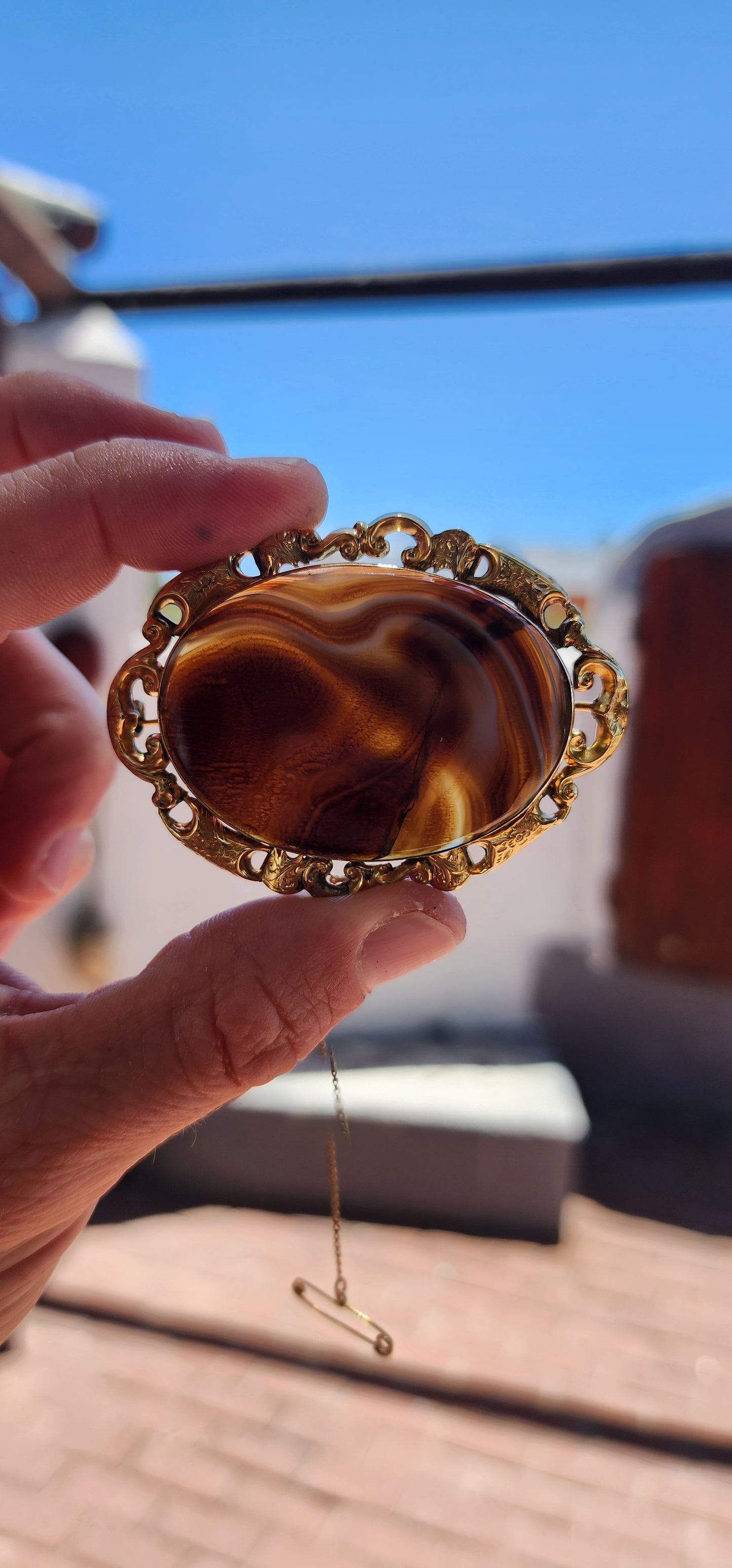 This oversized brooch is a fine example of an Antique Victorian-era Scottish banded agate brooch, crafted in 10ct yellow gold and featuring a large, polished oval banded agate at its center.