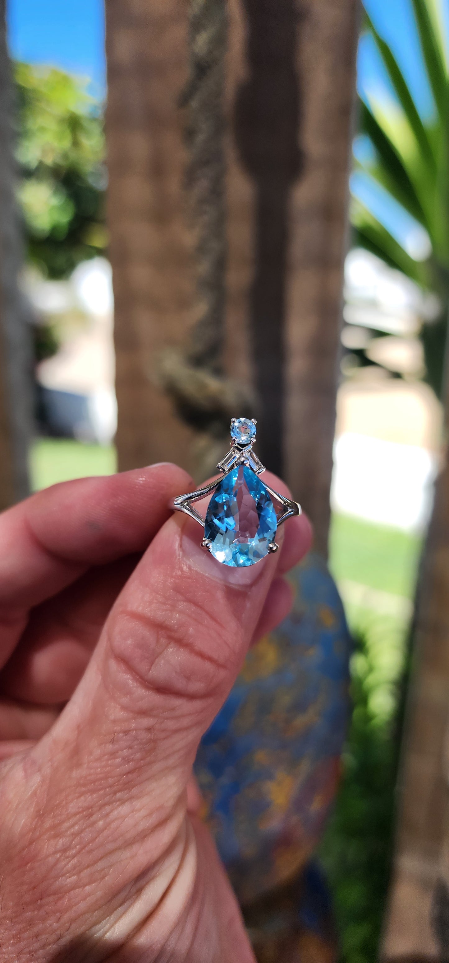 This Art Deco-inspired sterling silver ring is an absolute showstopper! At its heart lies a stunning, pear-cut Swiss blue topaz that radiates an ocean-like brilliance, its generous size drawing all eyes to its dazzling hue.