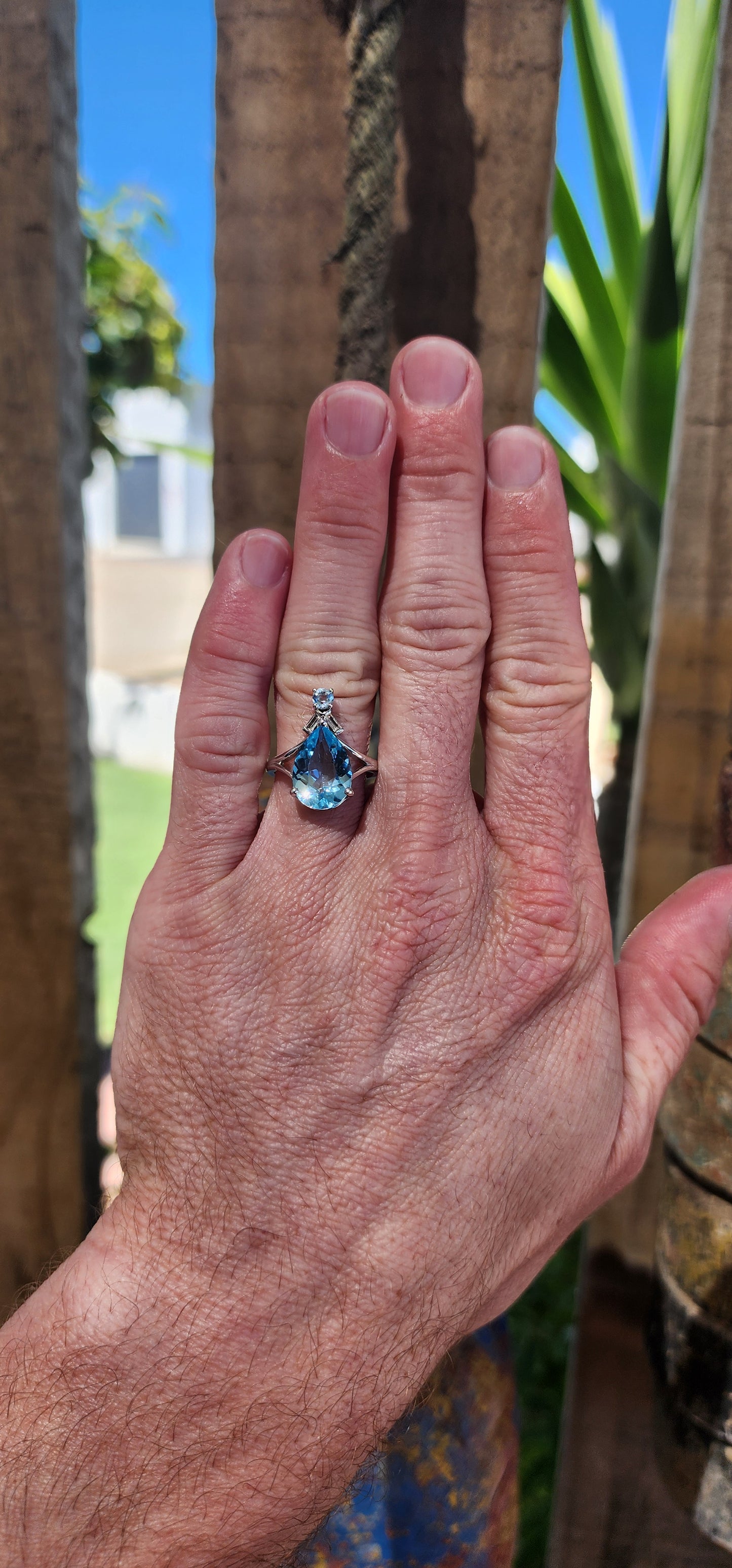 This Art Deco-inspired sterling silver ring is an absolute showstopper! At its heart lies a stunning, pear-cut Swiss blue topaz that radiates an ocean-like brilliance, its generous size drawing all eyes to its dazzling hue.