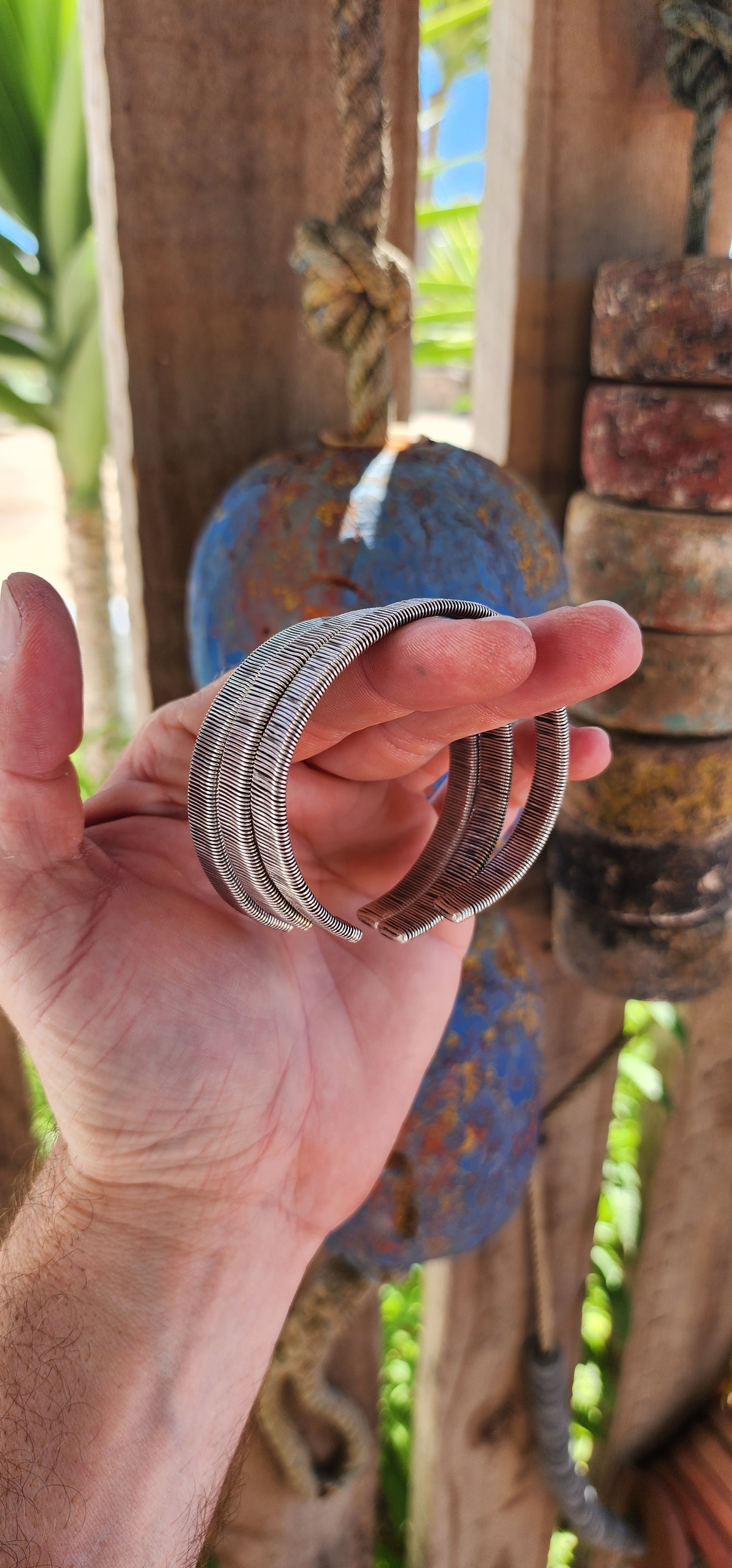 These bangles are a lot of three vintage Karen Hill Tribe open cuff bangles, crafted from solid 999 silver. Their weighty and solid nature, along with the intricate wrapped wire design, makes them unique pieces with both aesthetic and cultural value.