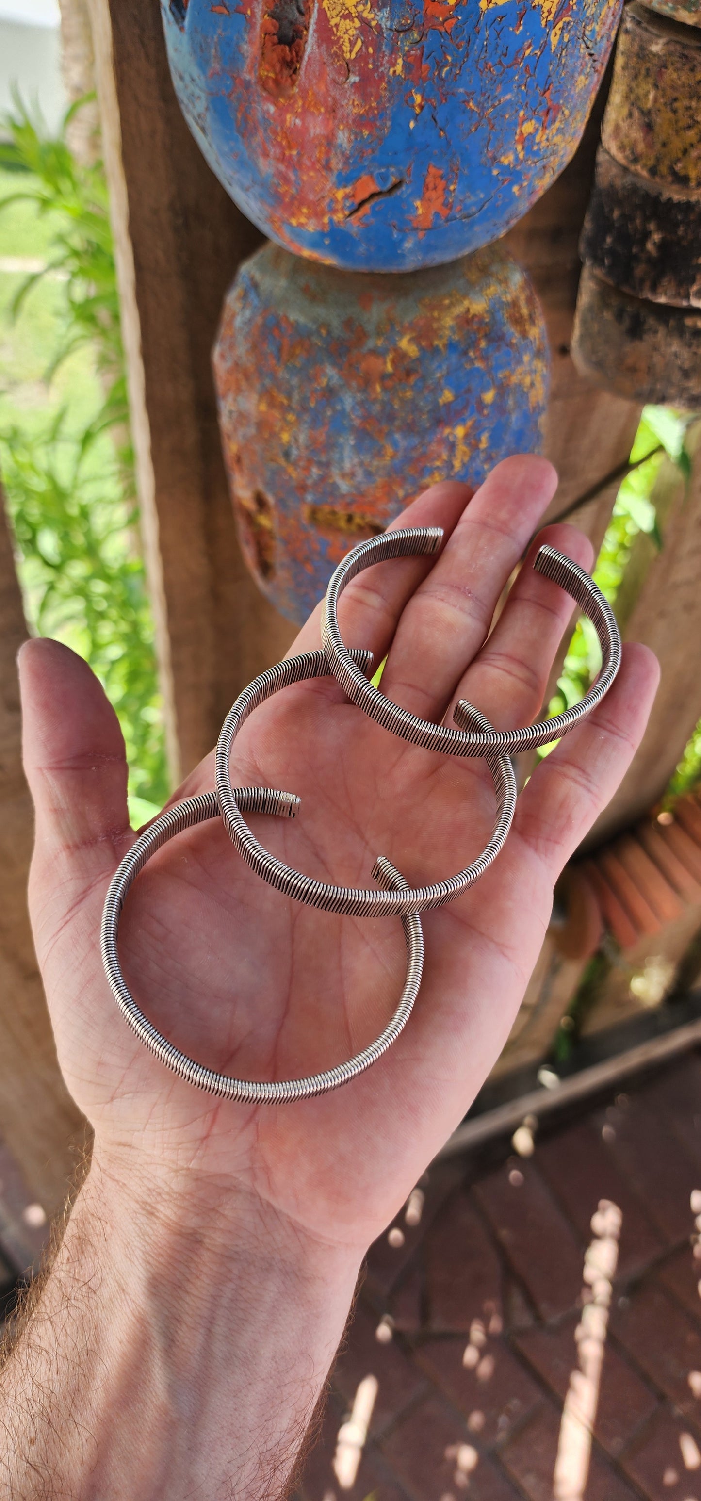 These bangles are a lot of three vintage Karen Hill Tribe open cuff bangles, crafted from solid 999 silver. Their weighty and solid nature, along with the intricate wrapped wire design, makes them unique pieces with both aesthetic and cultural value.
