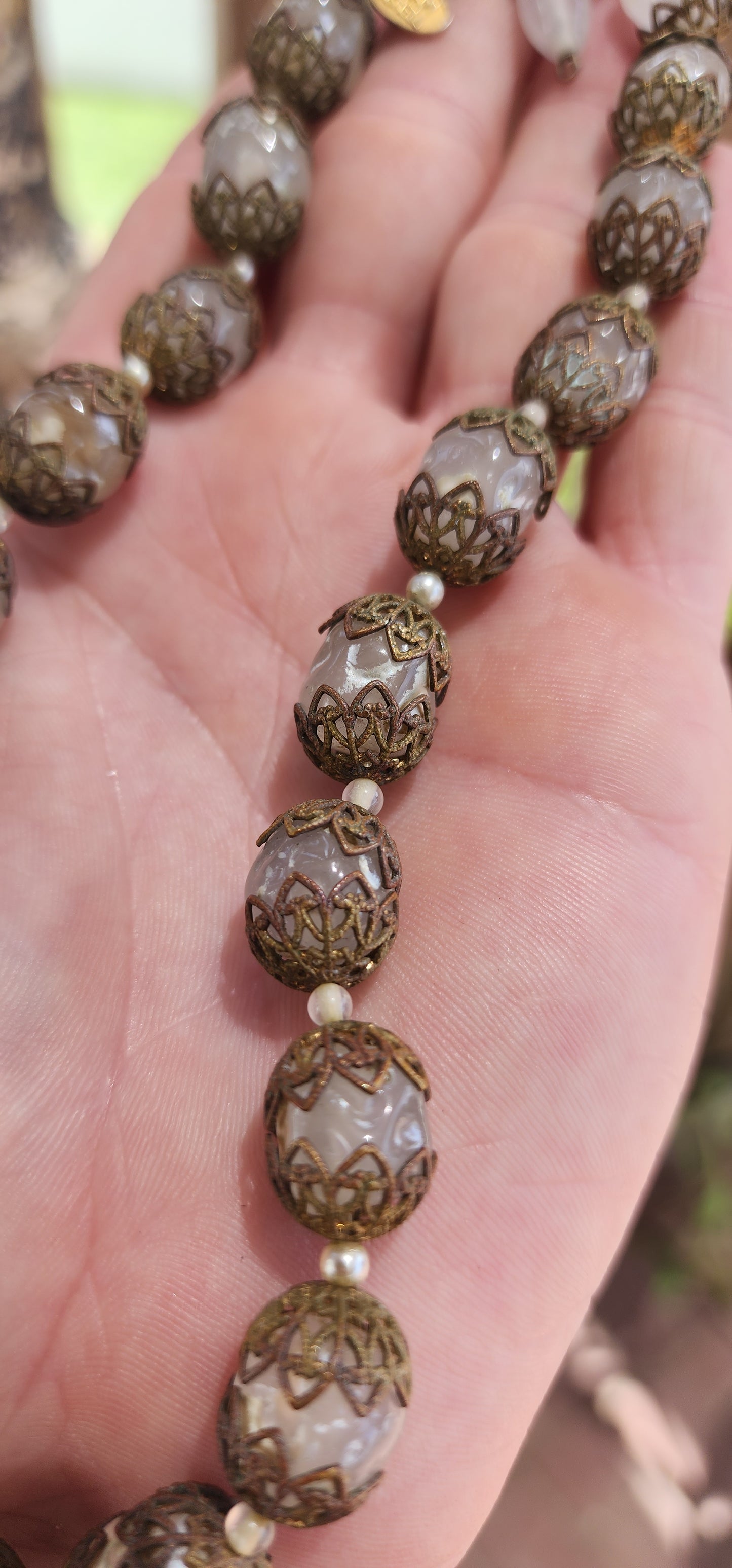 This exquisite Miriam Haskell costume necklace is a vintage choker-length piece from the 1970s, featuring opaque clear glass beads that are capped with ornate brass filigree.
