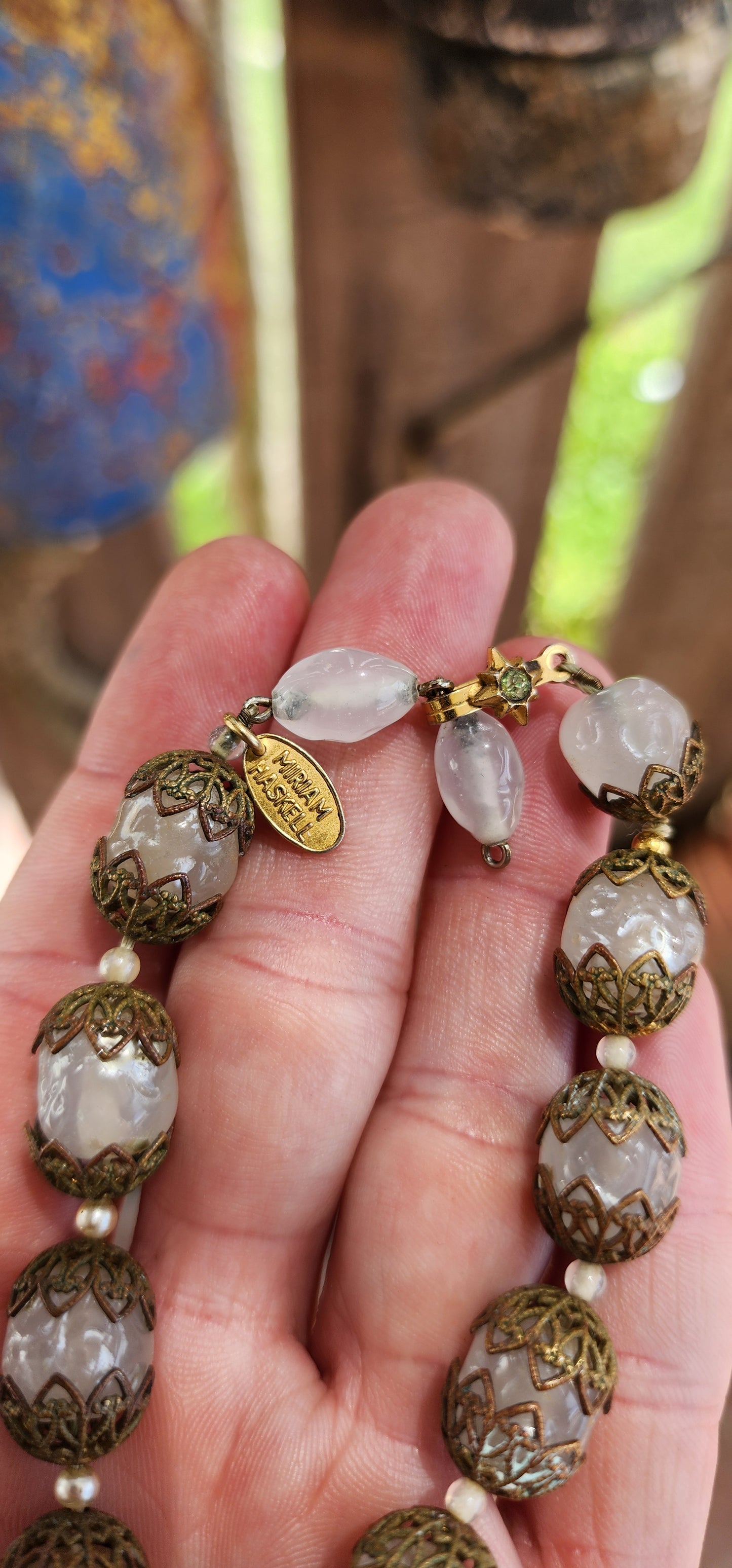 This exquisite Miriam Haskell costume necklace is a vintage choker-length piece from the 1970s, featuring opaque clear glass beads that are capped with ornate brass filigree.