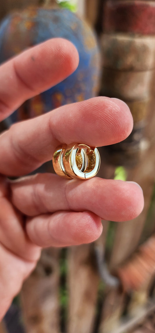 These sterling silver huggie earrings, plated with a radiant layer of 9ct yellow gold, embody the perfect blend of modern minimalism and classic elegance.
