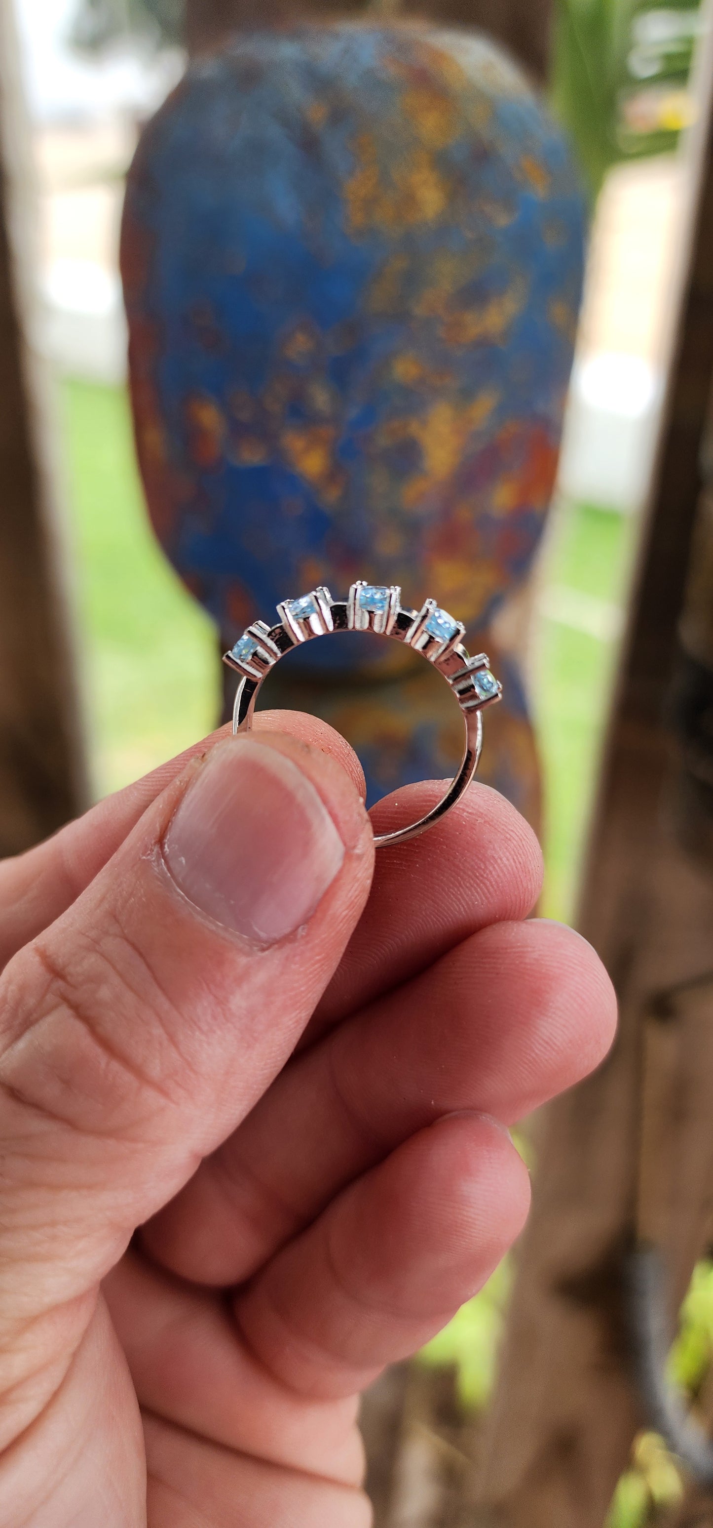 This sterling silver half-eternity ring is a refined and elegant piece, featuring five exquisite oval-cut sky blue topaz gemstones in a prong setting. The stones are arranged in a continuous row across the top of the band.