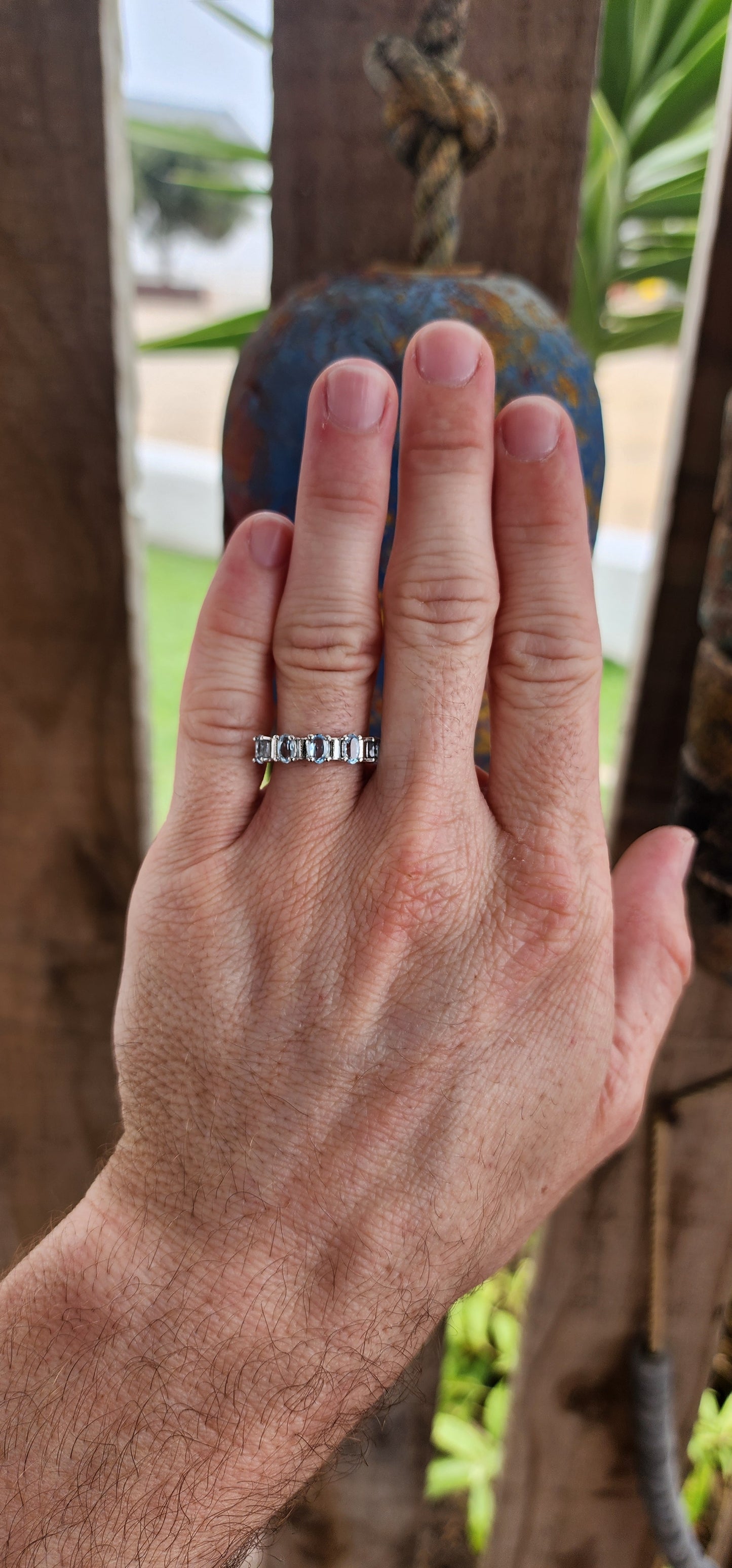 This sterling silver half-eternity ring is a refined and elegant piece, featuring five exquisite oval-cut sky blue topaz gemstones in a prong setting. The stones are arranged in a continuous row across the top of the band.