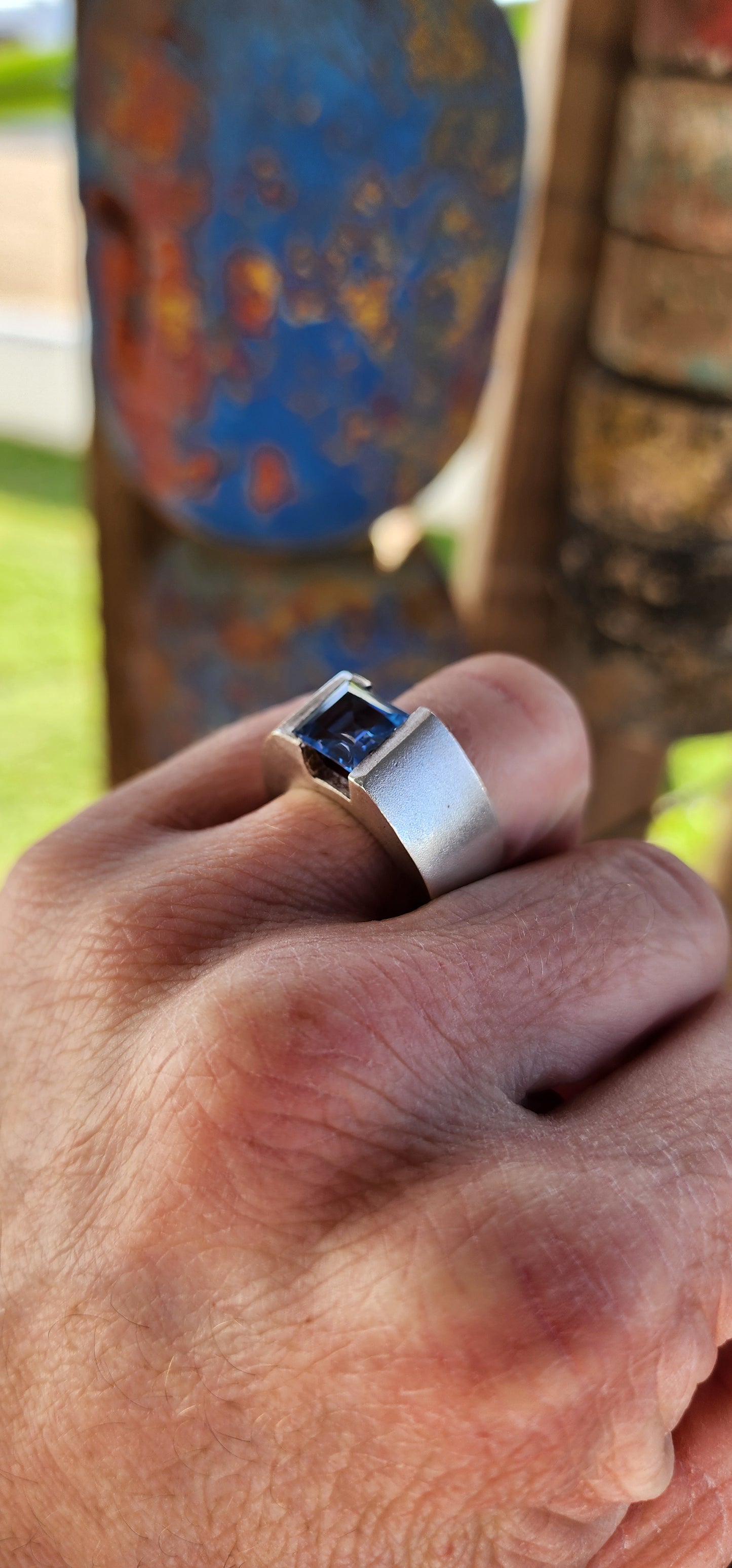 This striking artisan-made unisex statement ring is a bold fusion of modernist design and timeless craftsmanship. Crafted from solid sterling silver, the ring boasts a substantial, weighty presence on the hand, making it an undeniable statement piece.