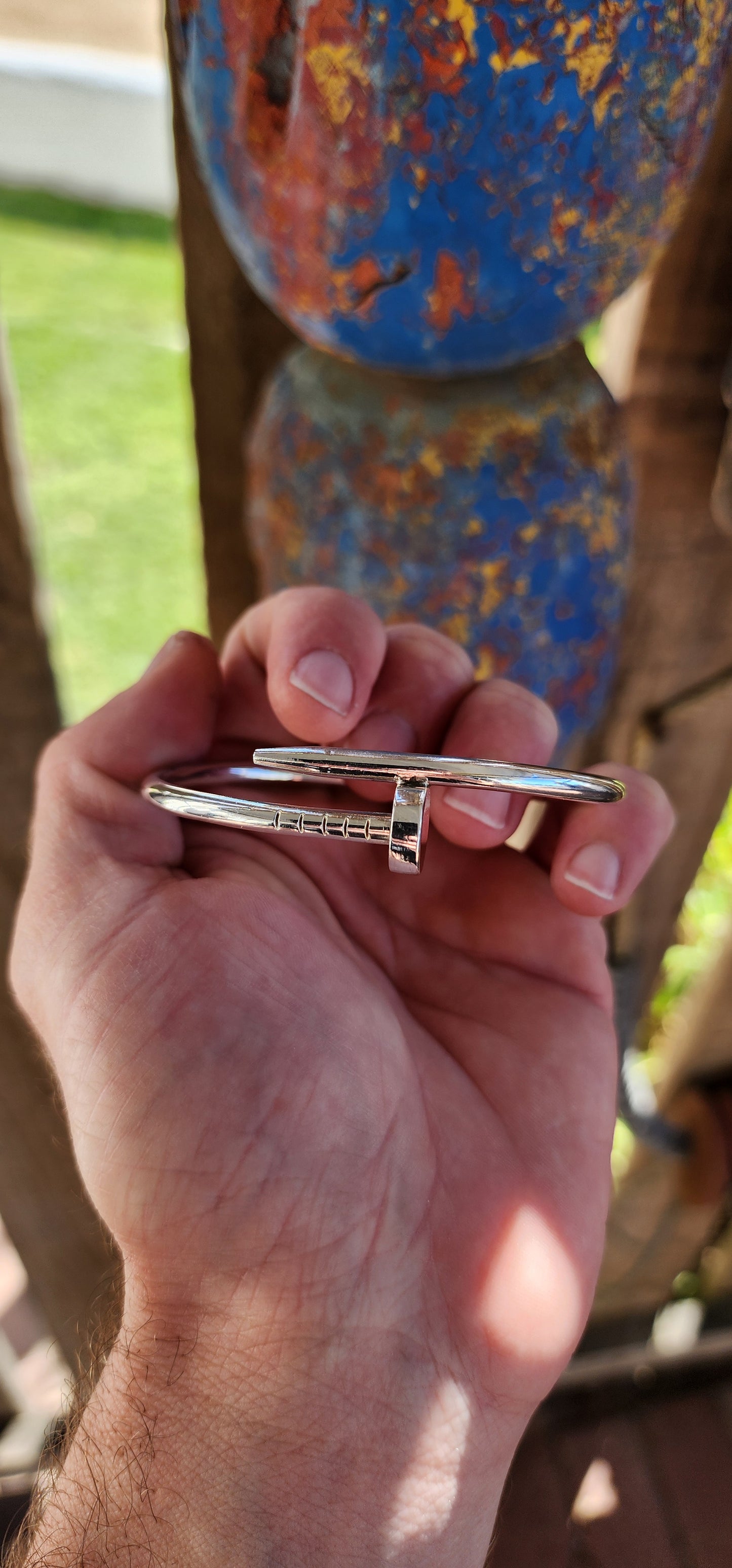 This solid sterling silver nail clip-bangle is a bold, industrial-chic statement piece that fuses rugged edge with high fashion elegance.