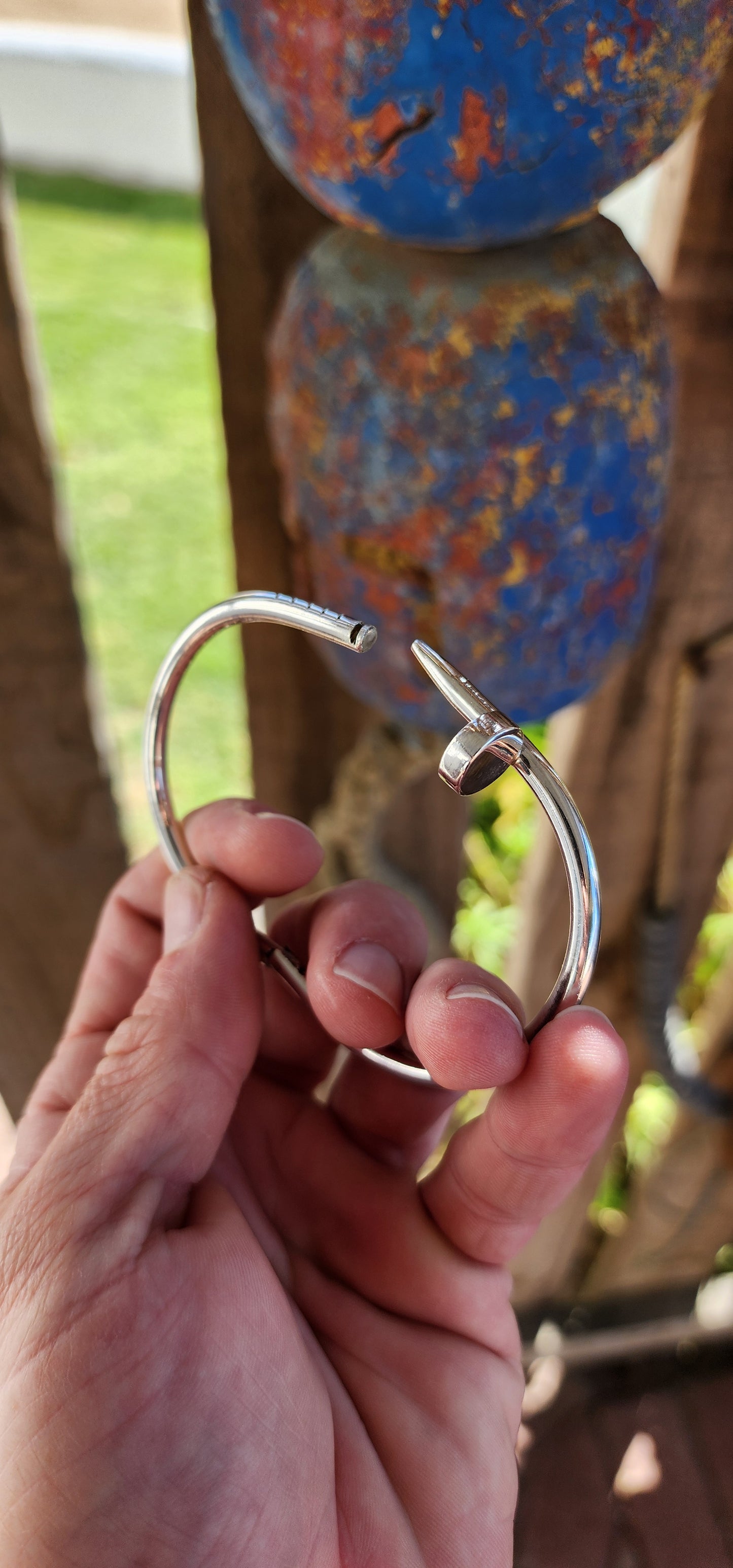 This solid sterling silver nail clip-bangle is a bold, industrial-chic statement piece that fuses rugged edge with high fashion elegance.