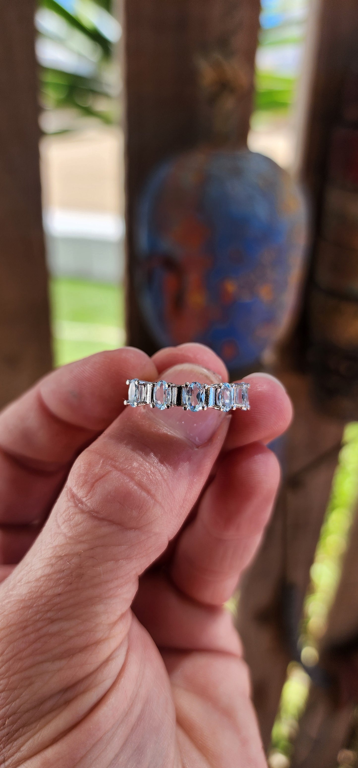 This sterling silver half-eternity ring is a refined and elegant piece, featuring five exquisite oval-cut sky blue topaz gemstones in a prong setting.