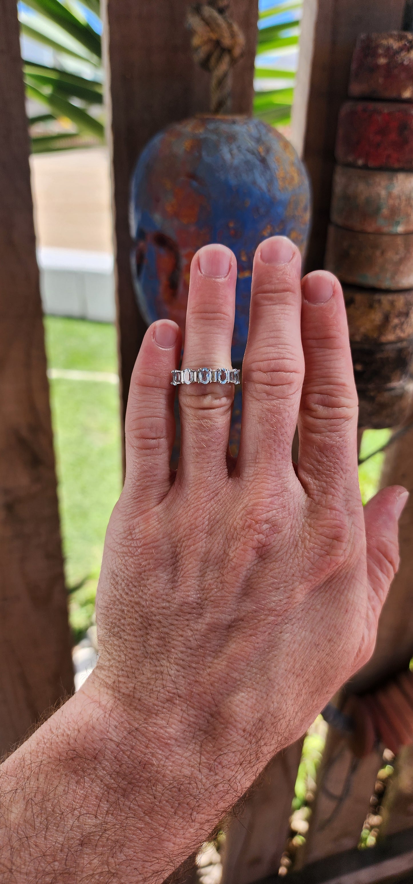 This sterling silver half-eternity ring is a refined and elegant piece, featuring five exquisite oval-cut sky blue topaz gemstones in a prong setting.
