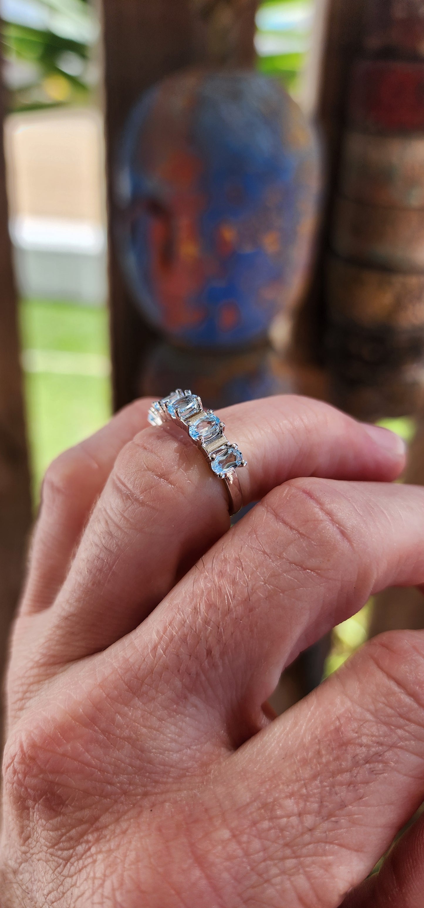 This sterling silver half-eternity ring is a refined and elegant piece, featuring five exquisite oval-cut sky blue topaz gemstones in a prong setting.