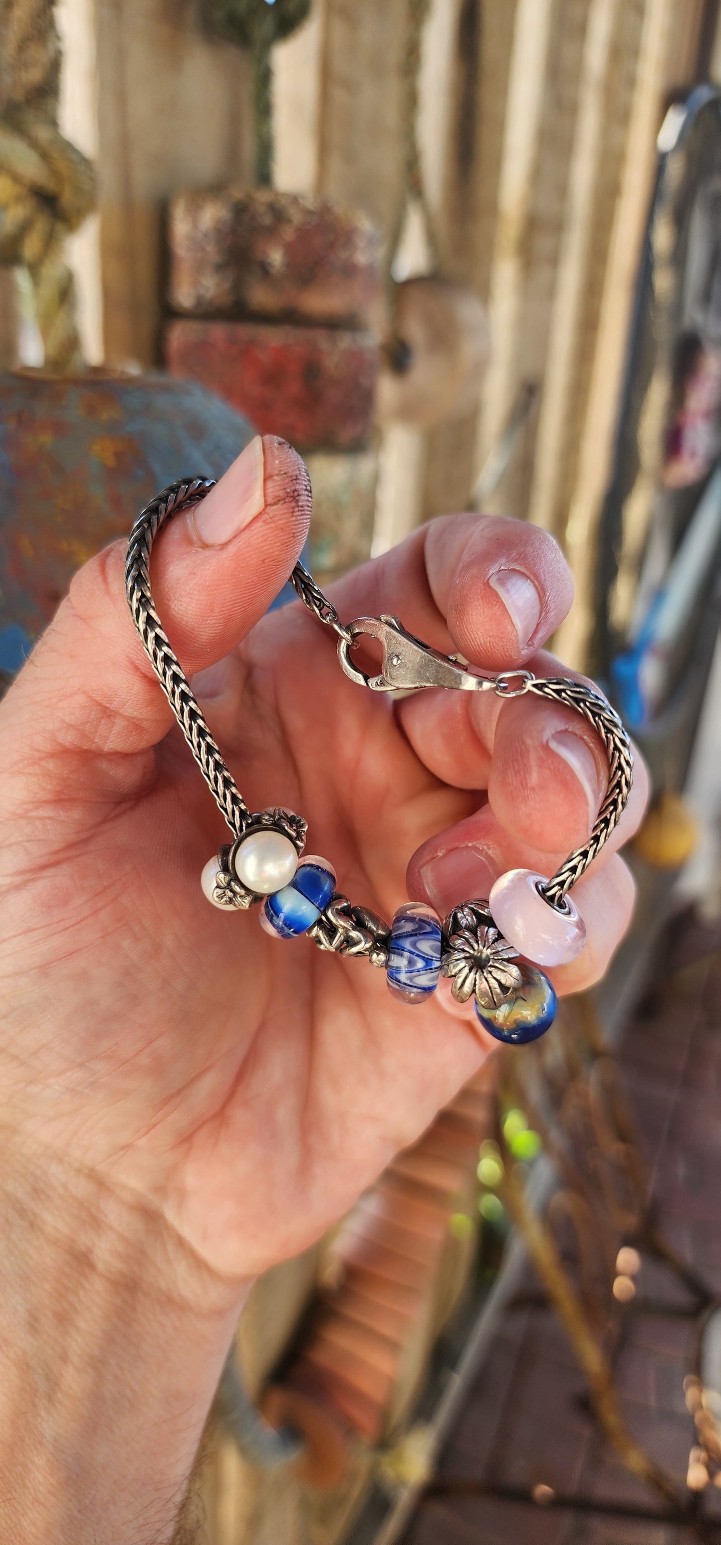 This T-r-o-l-l-b-e-a-d-s sterling silver charm bracelet is an exquisite piece that beautifully blends craftsmanship, storytelling, and luxury.