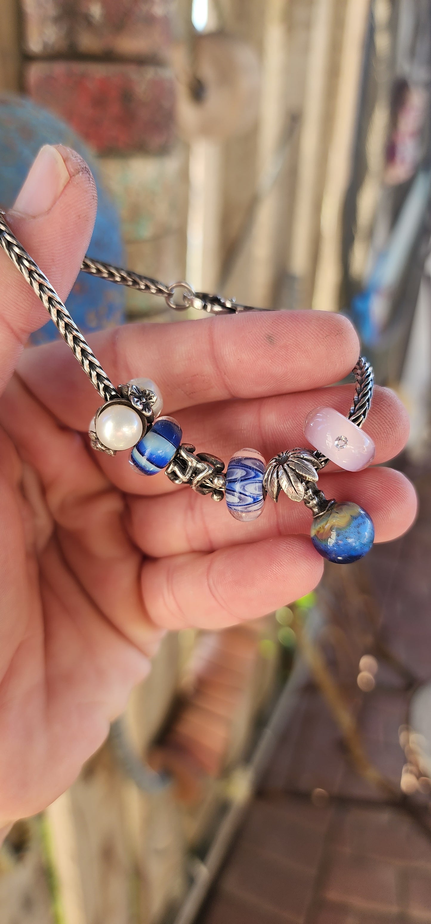 This T-r-o-l-l-b-e-a-d-s sterling silver charm bracelet is an exquisite piece that beautifully blends craftsmanship, storytelling, and luxury.