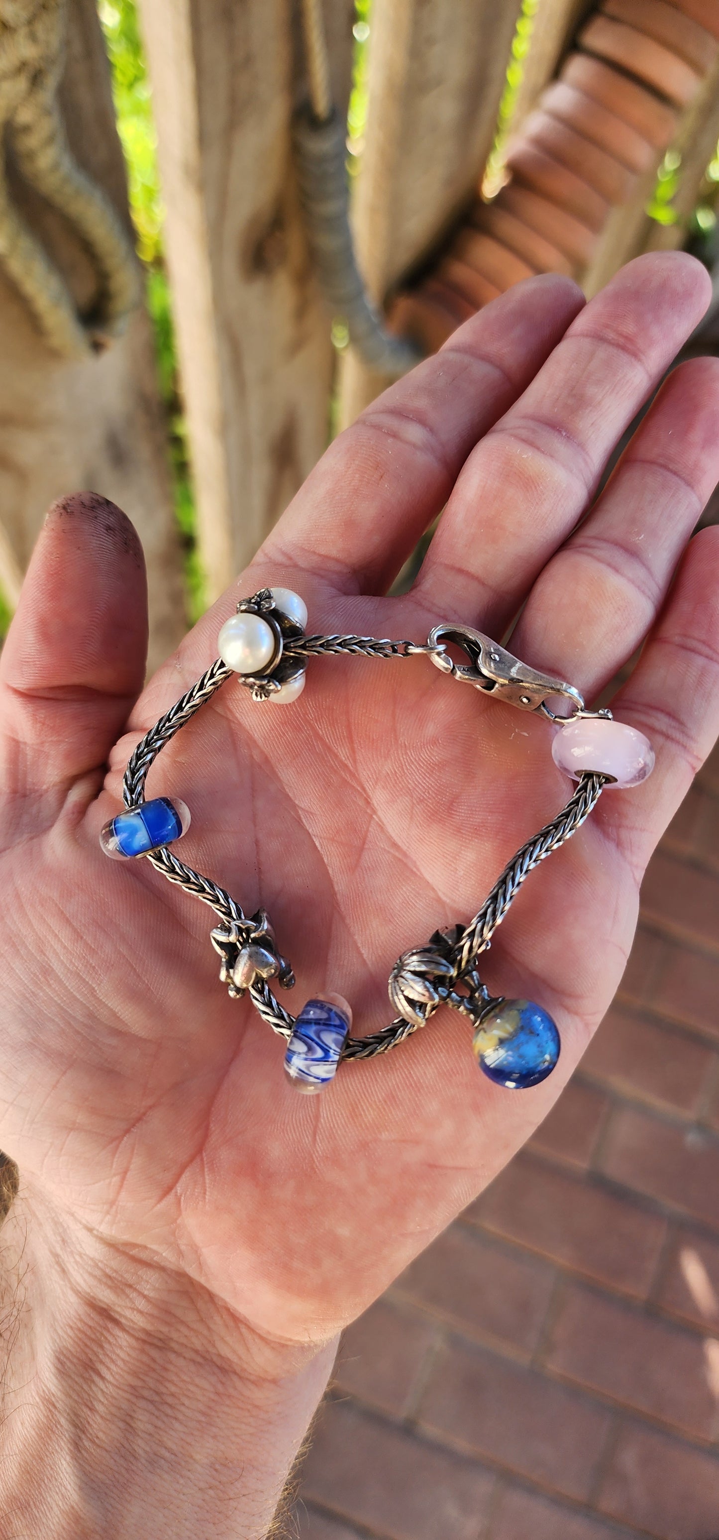 This T-r-o-l-l-b-e-a-d-s sterling silver charm bracelet is an exquisite piece that beautifully blends craftsmanship, storytelling, and luxury.