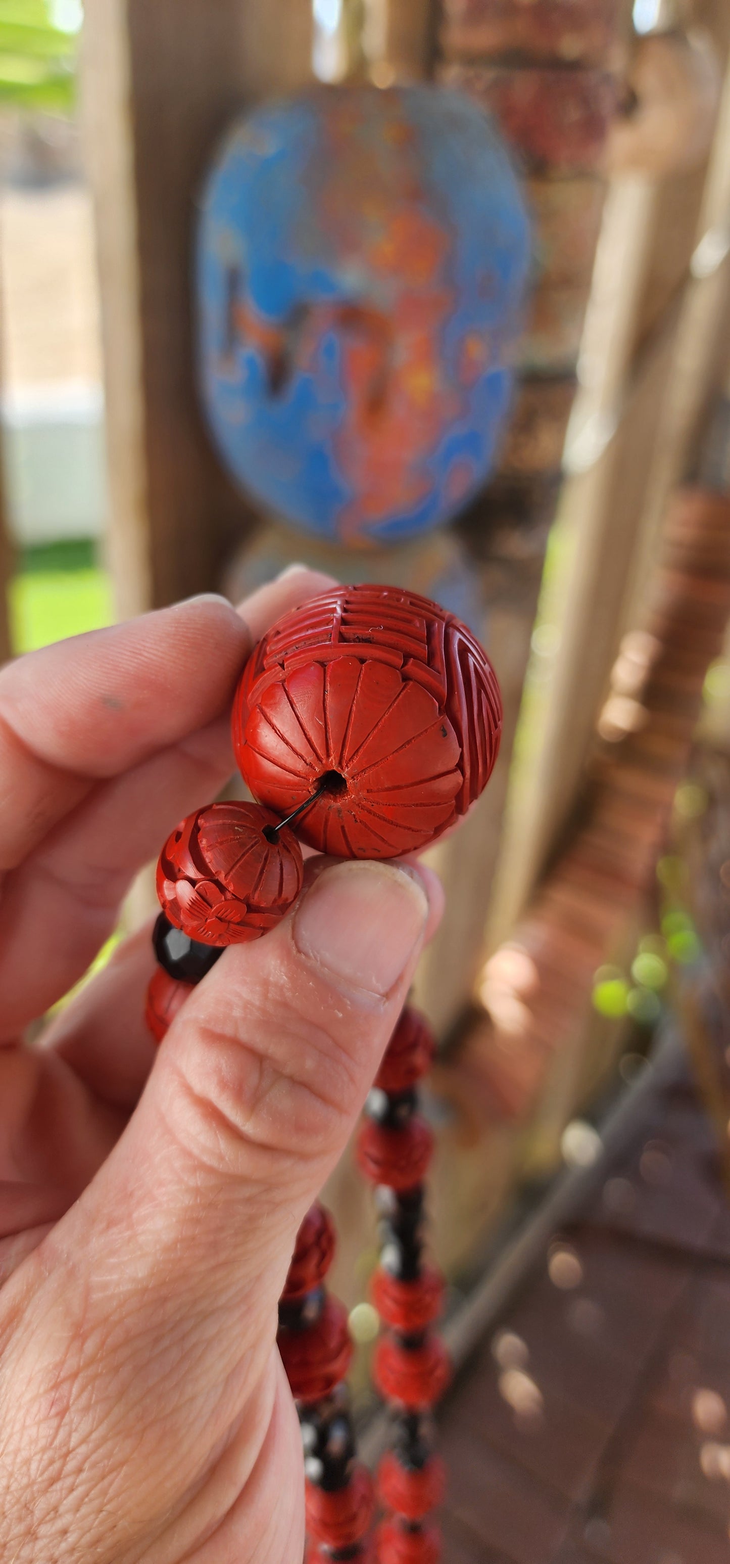 This vintage mid 20th century Chinese export necklace is a stunning example of traditional craftsmanship, featuring hand-carved cinnabar lacquer beads, faceted French jet glass beads, and a sterling silver magnetic clasp.