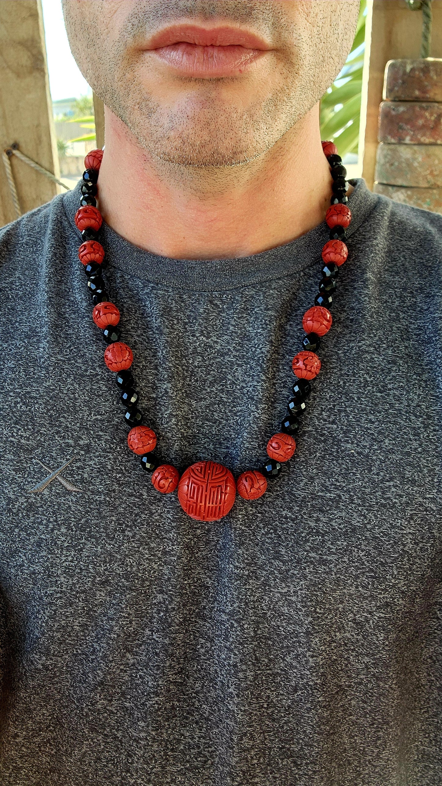 This vintage mid 20th century Chinese export necklace is a stunning example of traditional craftsmanship, featuring hand-carved cinnabar lacquer beads, faceted French jet glass beads, and a sterling silver magnetic clasp.