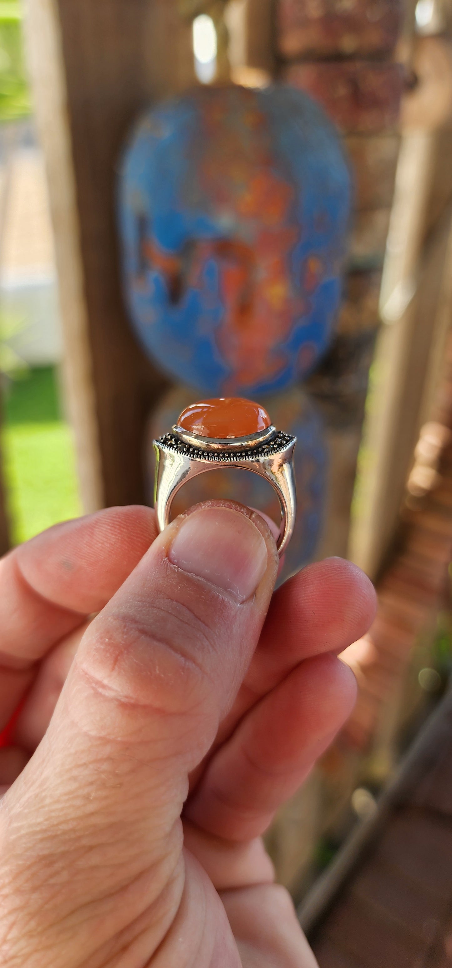 This chunky sterling silver statement dress ring is a striking fusion of bold design and vintage charm, exuding an air of mystery and elegance. At its heart lies a mesmerizing oval orange moonstone cabochon, set securely in a smooth bezel setting.