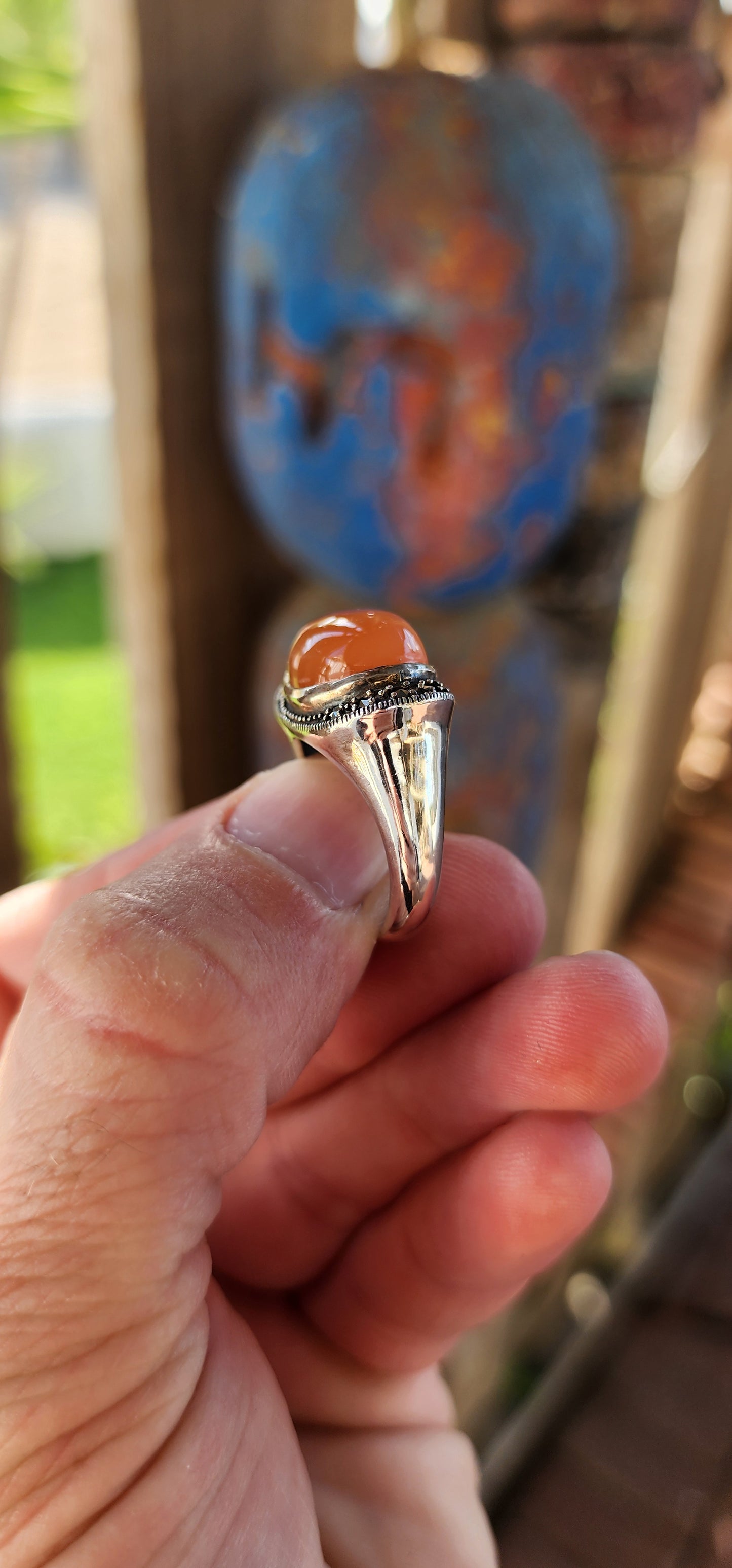 This chunky sterling silver statement dress ring is a striking fusion of bold design and vintage charm, exuding an air of mystery and elegance. At its heart lies a mesmerizing oval orange moonstone cabochon, set securely in a smooth bezel setting.