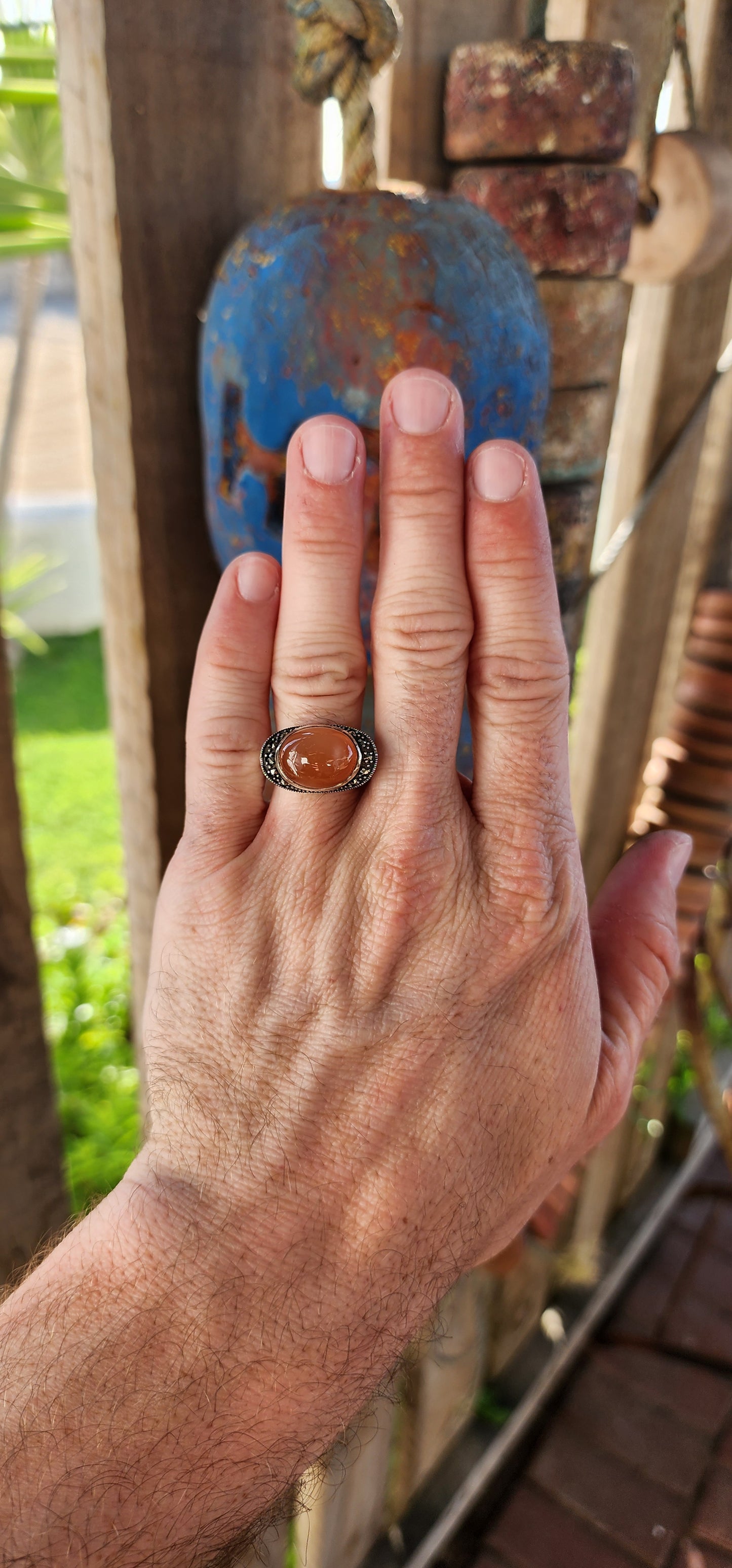 This chunky sterling silver statement dress ring is a striking fusion of bold design and vintage charm, exuding an air of mystery and elegance. At its heart lies a mesmerizing oval orange moonstone cabochon, set securely in a smooth bezel setting.