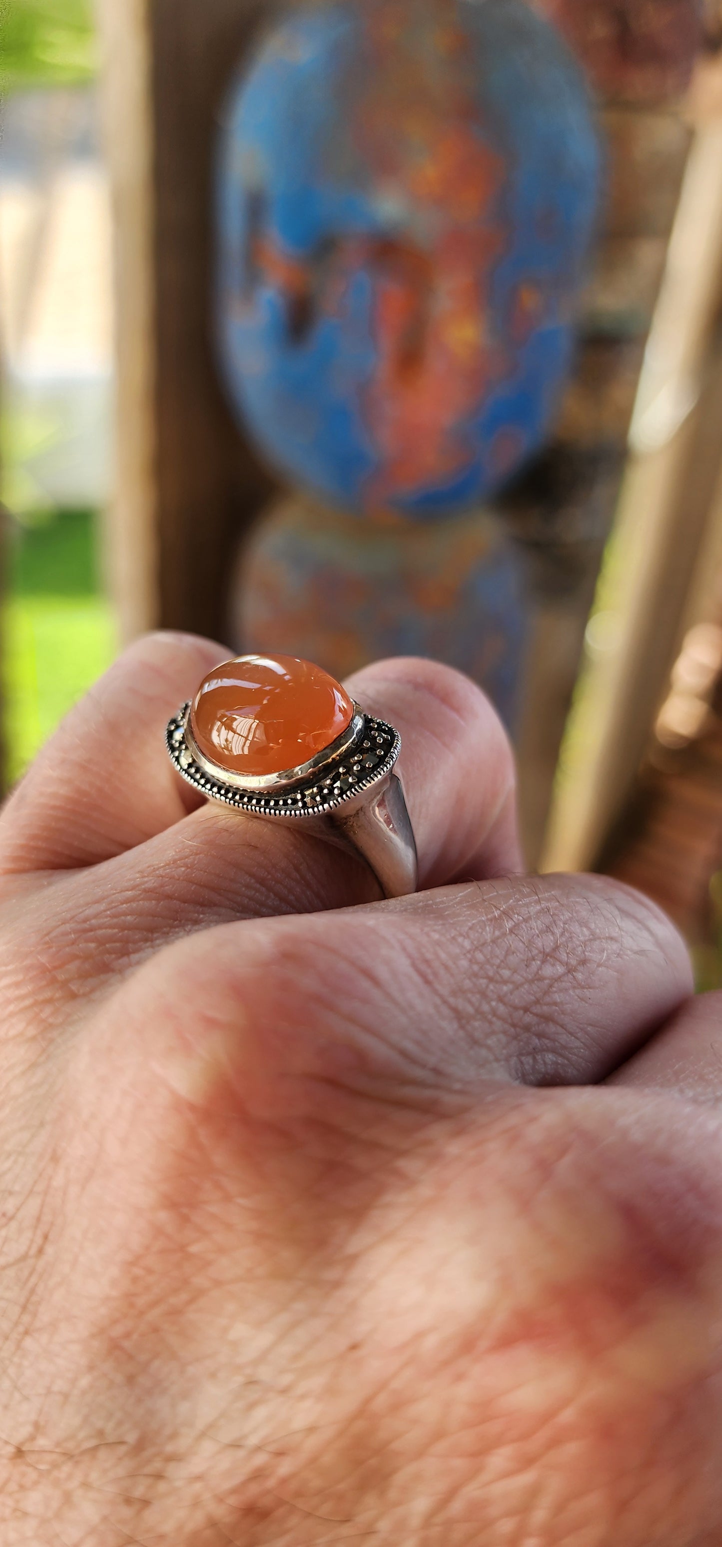 This chunky sterling silver statement dress ring is a striking fusion of bold design and vintage charm, exuding an air of mystery and elegance. At its heart lies a mesmerizing oval orange moonstone cabochon, set securely in a smooth bezel setting.