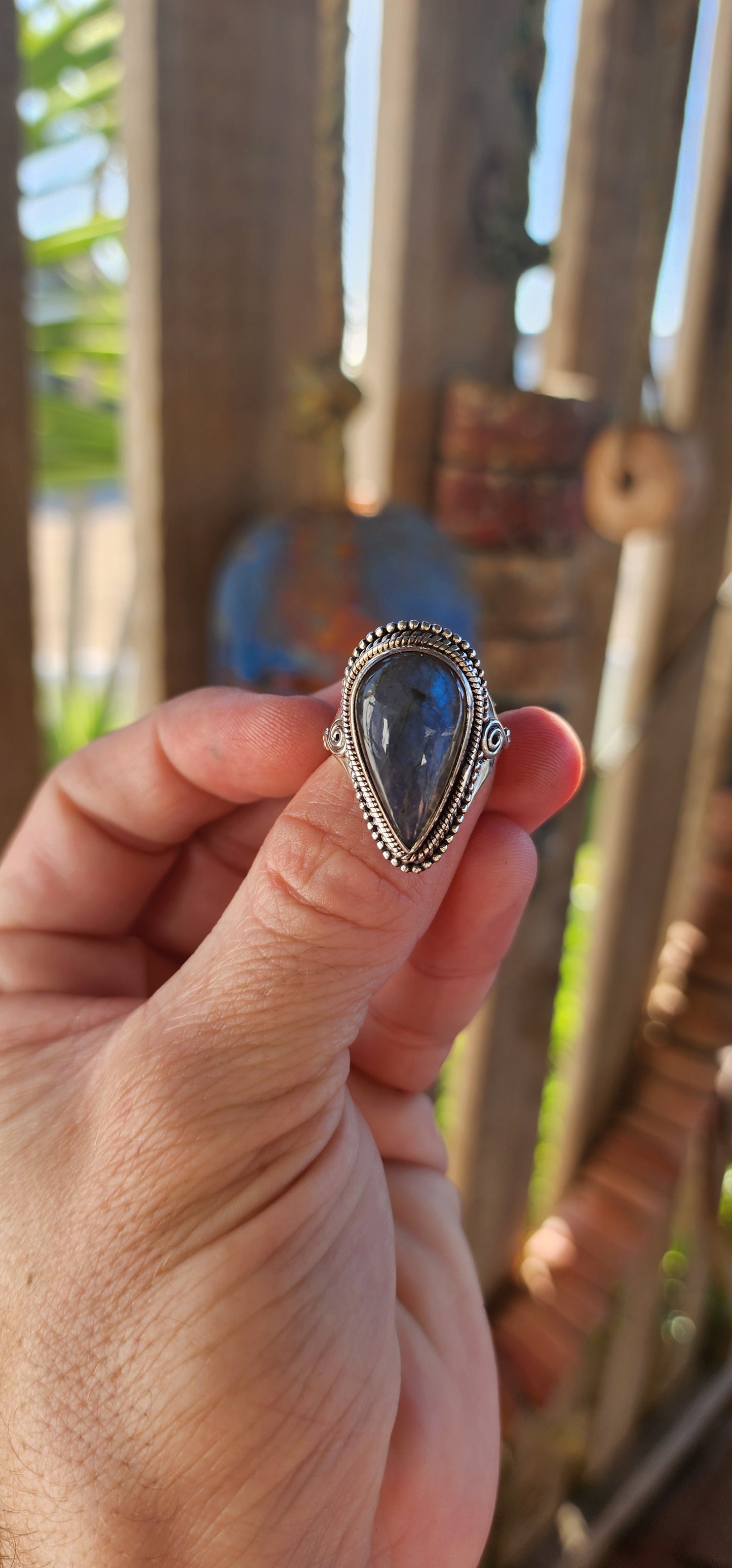 This is a commanding bohemian-gypsy sterling silver statement ring, designed with a harmonious blend of rugged elegance and artisanal charm. At its heart rests a generously sized, pear-shaped labradorite cabochon.