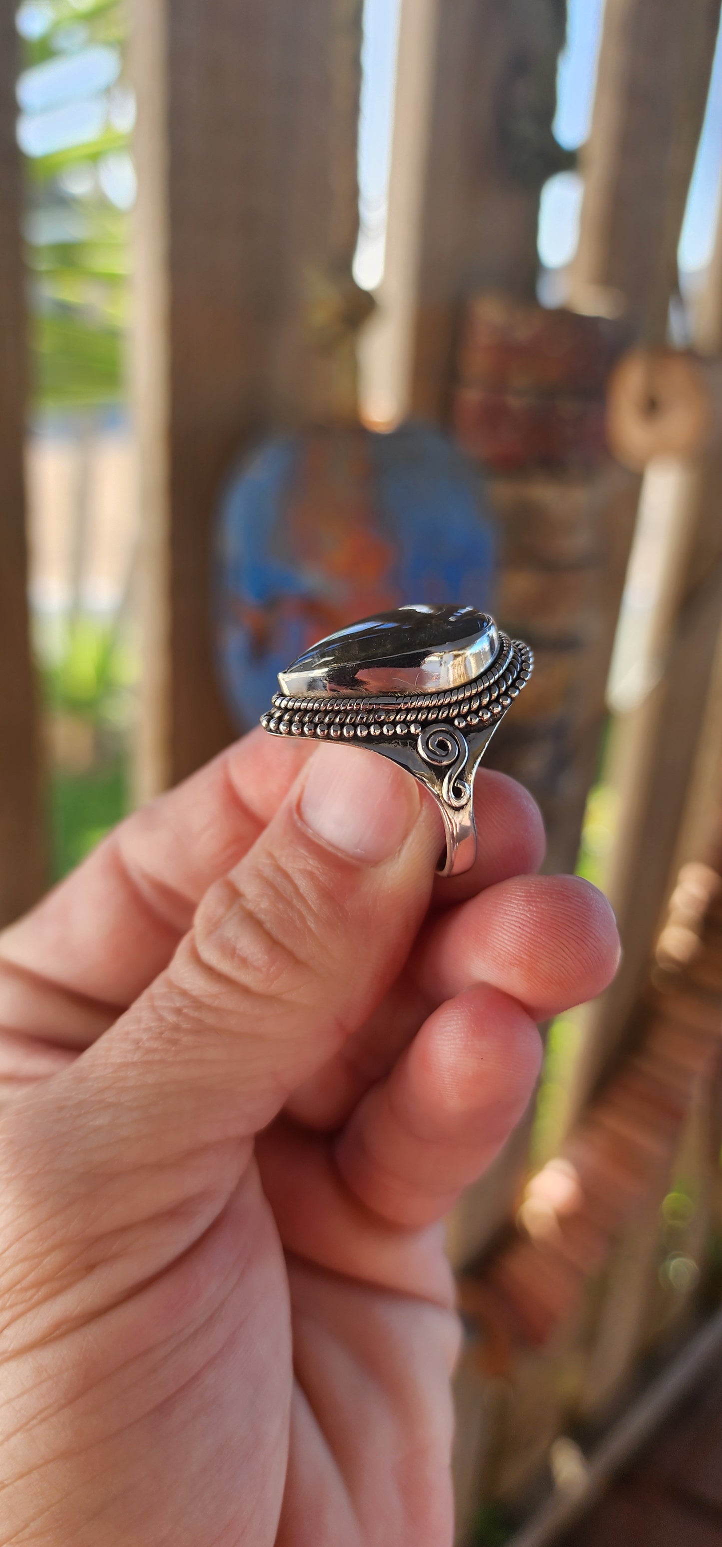 This is a commanding bohemian-gypsy sterling silver statement ring, designed with a harmonious blend of rugged elegance and artisanal charm. At its heart rests a generously sized, pear-shaped labradorite cabochon.