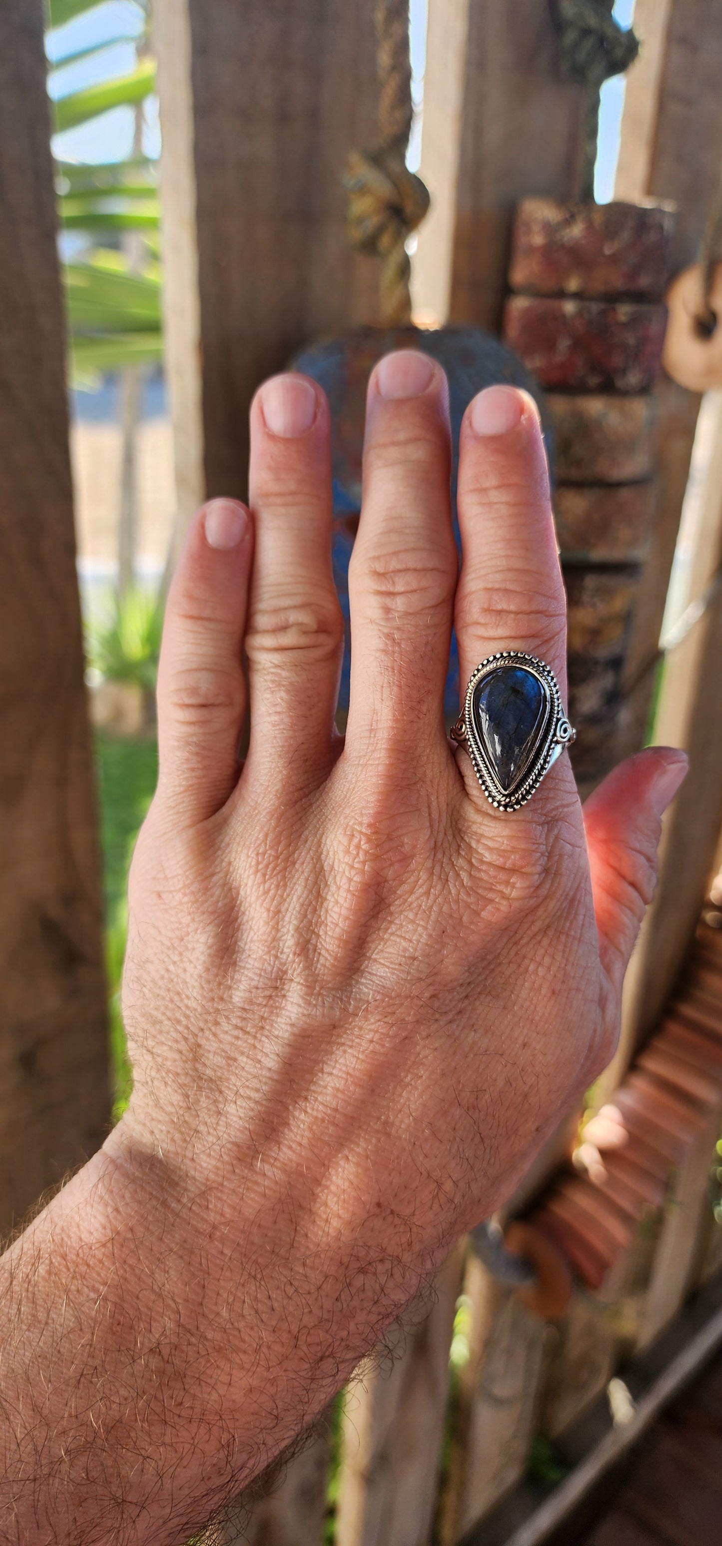 This is a commanding bohemian-gypsy sterling silver statement ring, designed with a harmonious blend of rugged elegance and artisanal charm. At its heart rests a generously sized, pear-shaped labradorite cabochon.