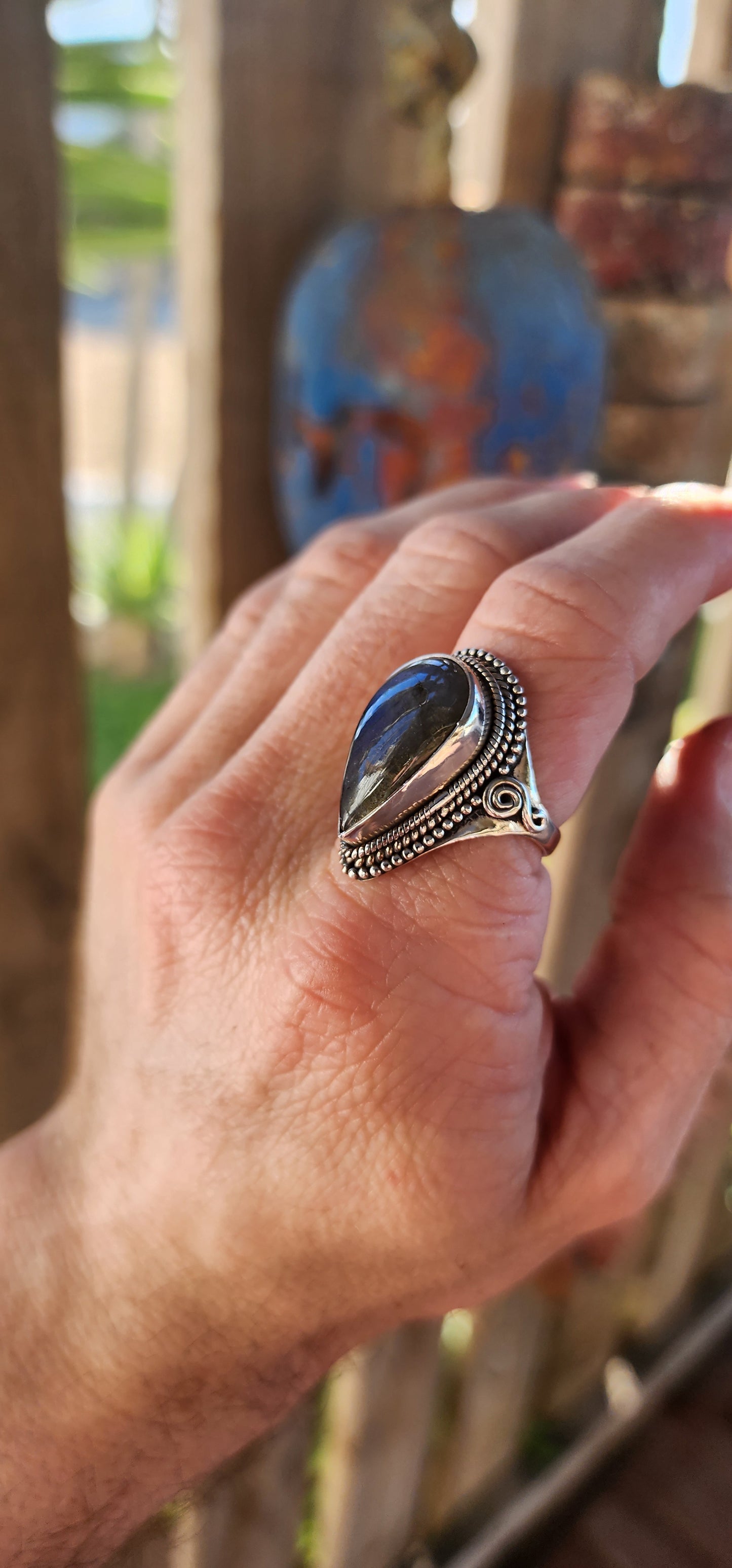 This is a commanding bohemian-gypsy sterling silver statement ring, designed with a harmonious blend of rugged elegance and artisanal charm. At its heart rests a generously sized, pear-shaped labradorite cabochon.