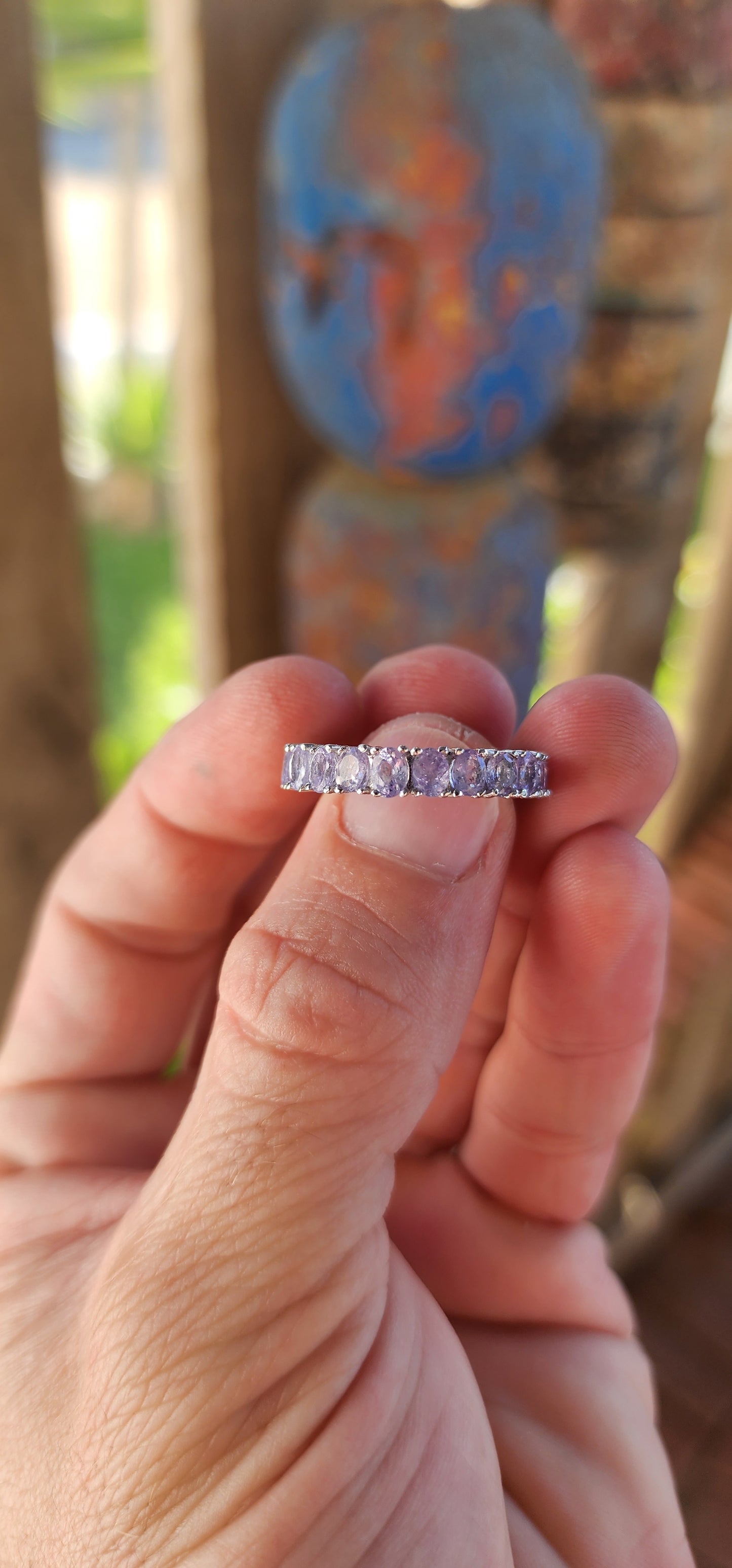 This exquisite full eternity ring is a testament to masterful craftsmanship and timeless elegance. Expertly forged in polished sterling silver, the ring showcases a seamless circle of 21 oval-cut Tanzanite gemstones.