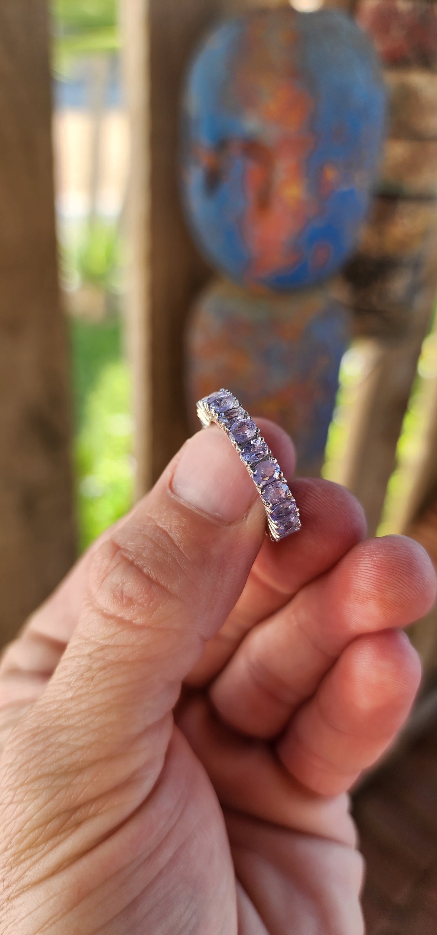 This exquisite full eternity ring is a testament to masterful craftsmanship and timeless elegance. Expertly forged in polished sterling silver, the ring showcases a seamless circle of 21 oval-cut Tanzanite gemstones.
