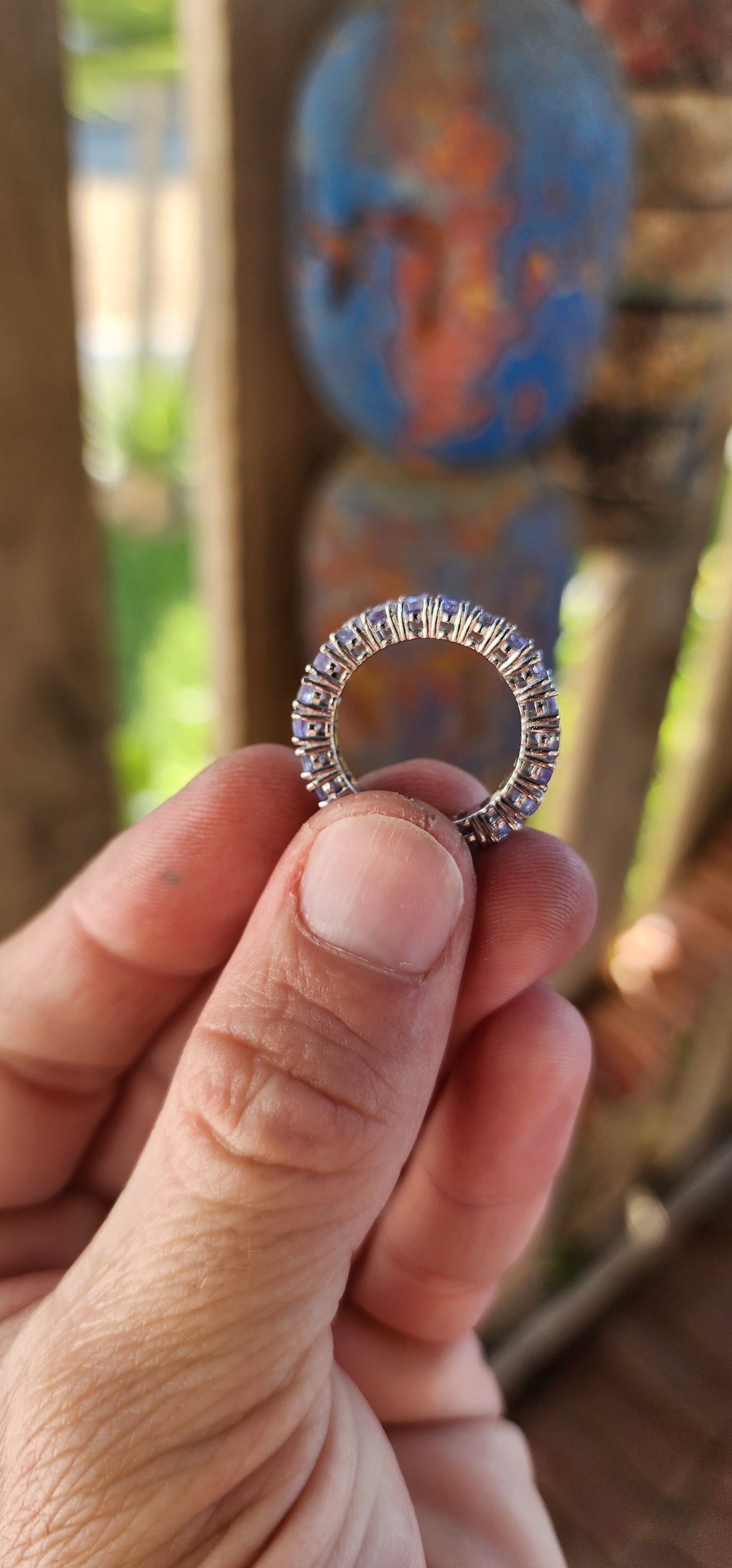 This exquisite full eternity ring is a testament to masterful craftsmanship and timeless elegance. Expertly forged in polished sterling silver, the ring showcases a seamless circle of 21 oval-cut Tanzanite gemstones.