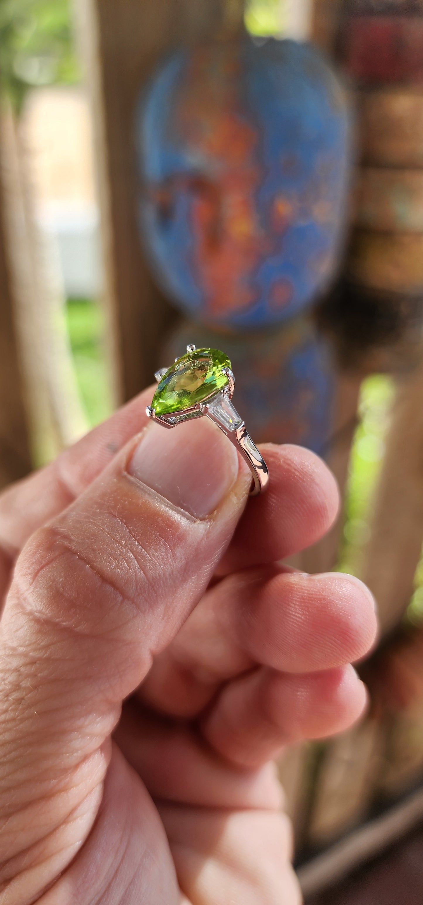 Say hello to this bold beauty — a sterling silver trilogy ring that’s practically glowing with zest and charm!
At its heart lies a mesmerizing, generously sized pear-cut peridot, gleaming in a vivid lime-green hue.