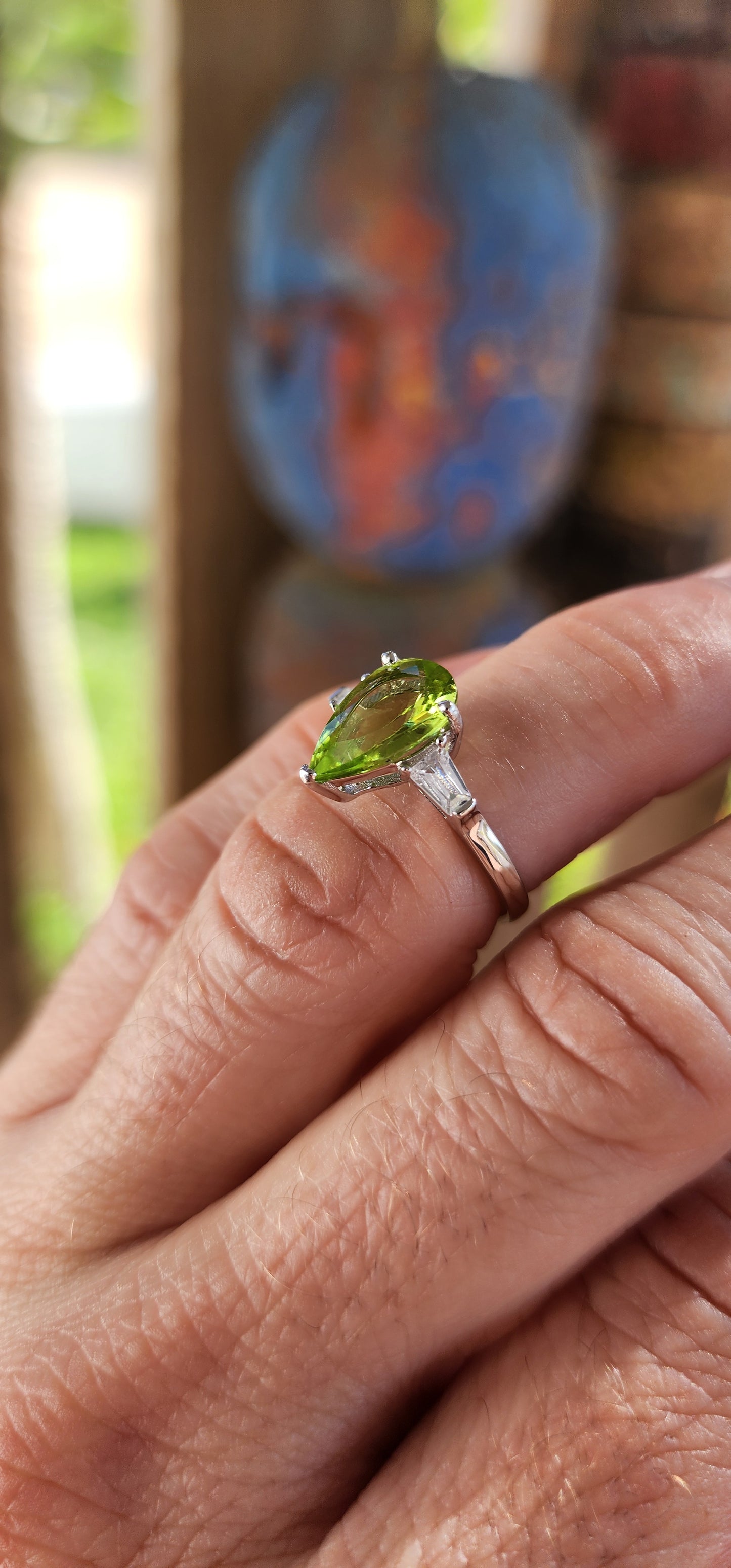 Say hello to this bold beauty — a sterling silver trilogy ring that’s practically glowing with zest and charm!
At its heart lies a mesmerizing, generously sized pear-cut peridot, gleaming in a vivid lime-green hue.