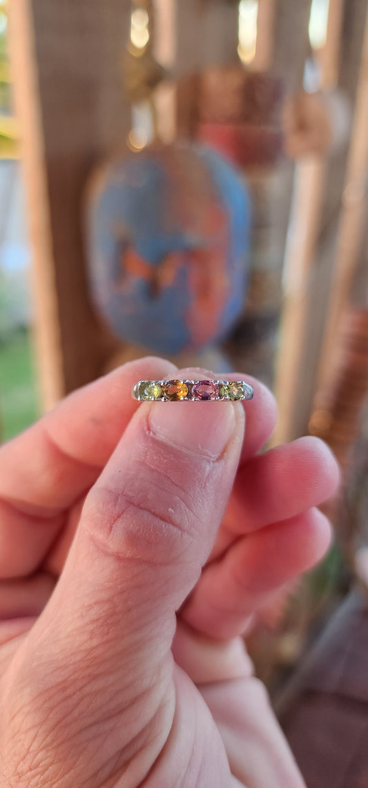 Let your fingers tell a story of color and wonder with this enchanting sterling silver half-eternity ring. Prong-set along the polished silver band are four oval-cut multi-colored tourmalines, each a glowing whisper of nature’s palette.