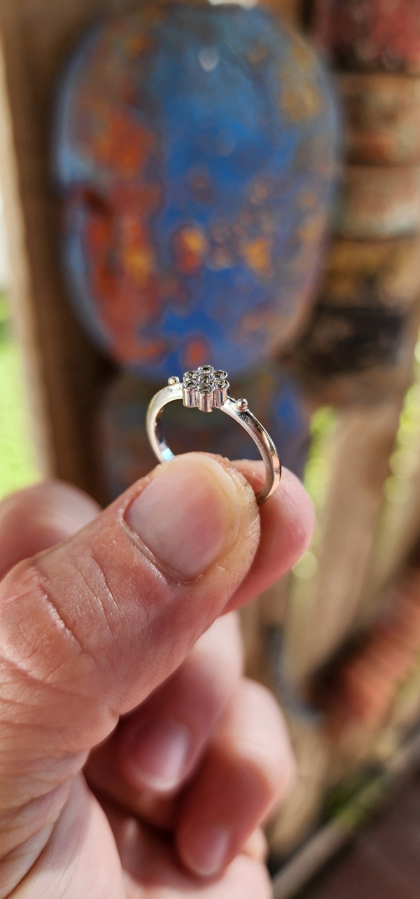 A timeless bloom of elegance—this vintage beauty is the epitome of delicate grace. Crafted in solid 18ct white gold, this charming ring features a petite flower cluster formed from seven small round cut white diamonds .